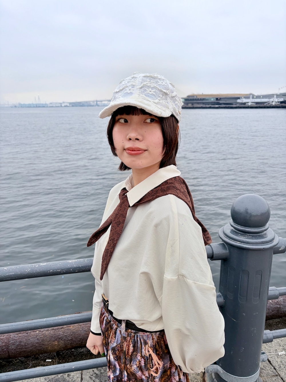 パープル系のパンツ、ブラック系のスニーカー、ホワイト系のキャップを着用したレディースの春コーディネートの6枚目の写真