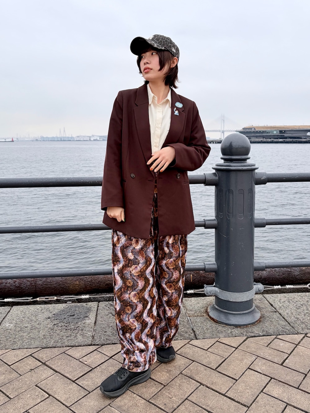 ブラウン系のテーラードジャケット、パープル系のパンツ、ブラック系のスニーカーを着用したレディースの春コーディネートの2枚目の写真