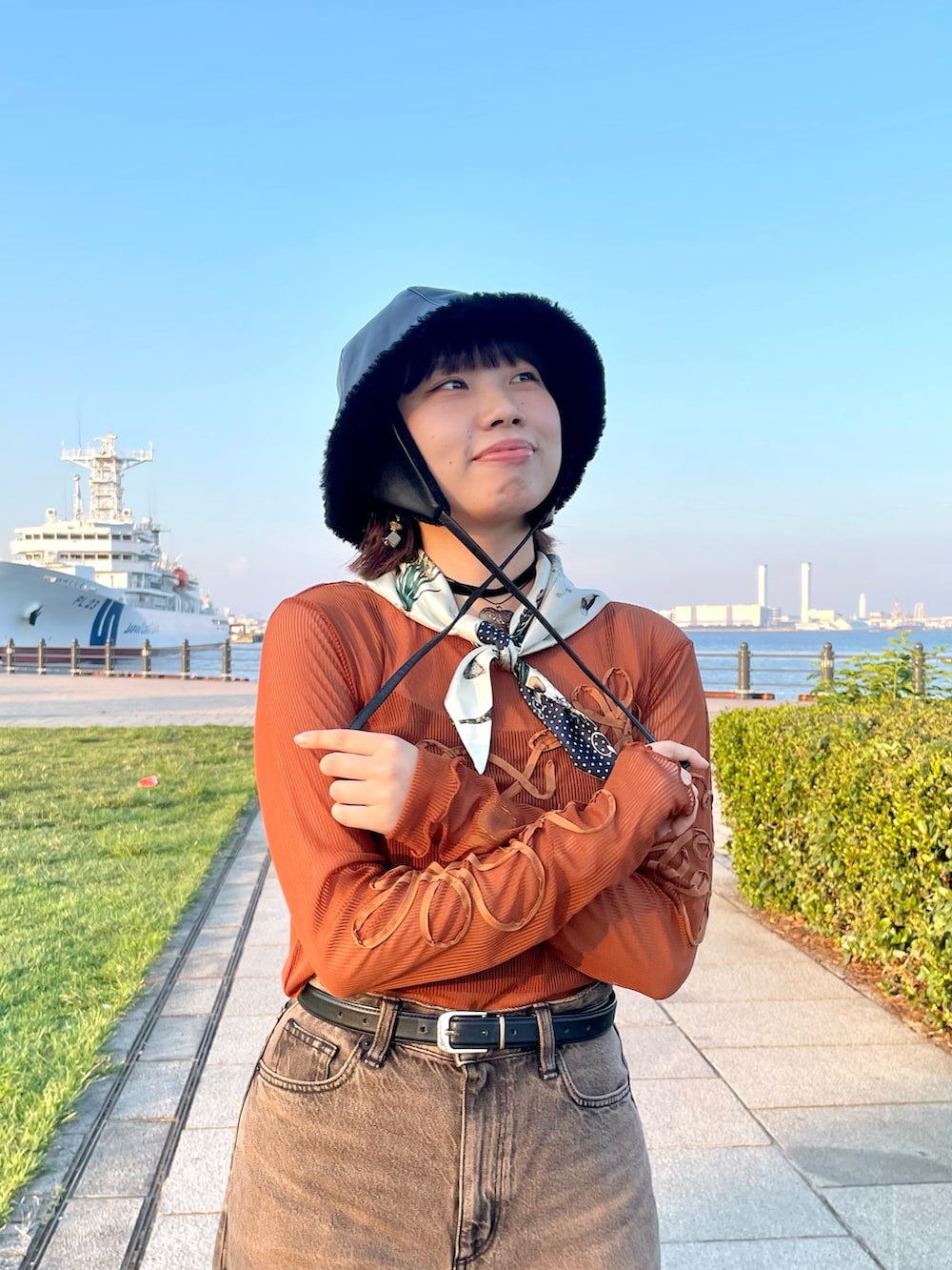 オレンジ系のTシャツ/カットソー、ブラウン系のデニムパンツ、ホワイト系のスニーカーを着用したレディースの秋コーディネートの7枚目の写真