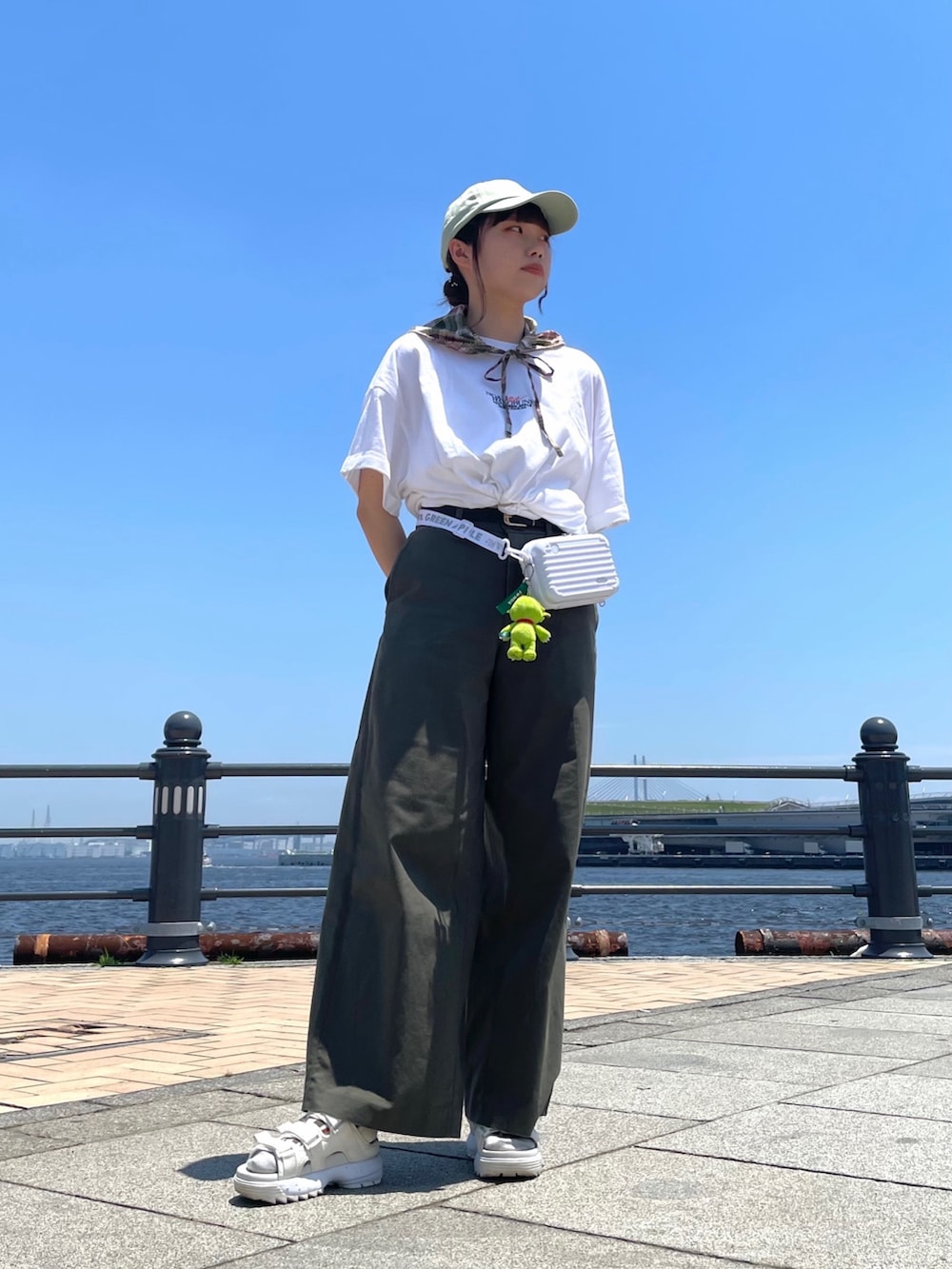 グリーン系のチノパンツ、ホワイト系のサンダル、グリーン系のキャップを着用したレディースの夏コーディネートの2枚目の写真