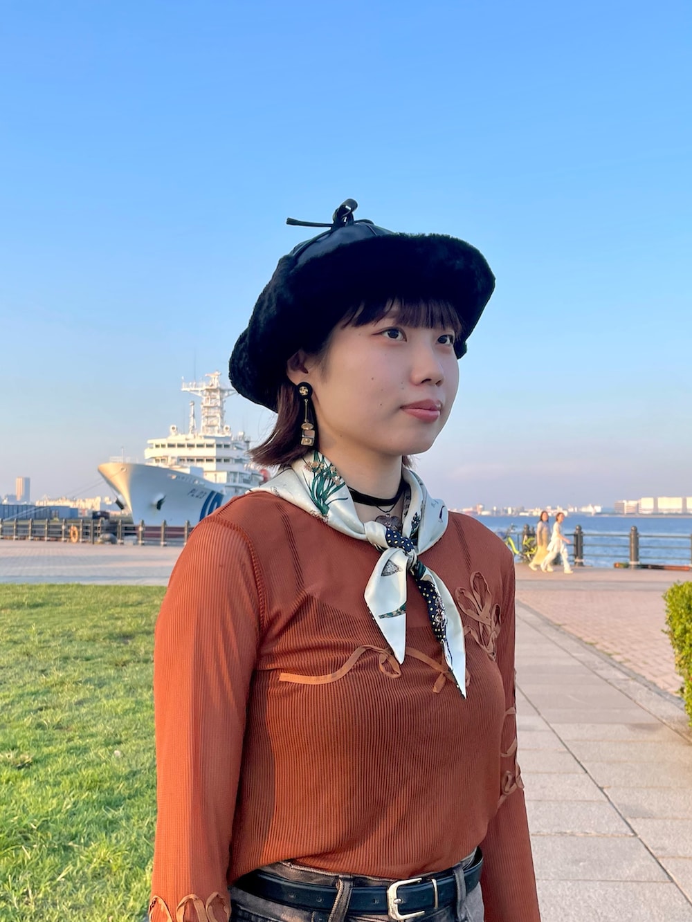 オレンジ系のTシャツ/カットソー、ブラウン系のデニムパンツ、ホワイト系のスニーカーを着用したレディースの秋コーディネートの6枚目の写真