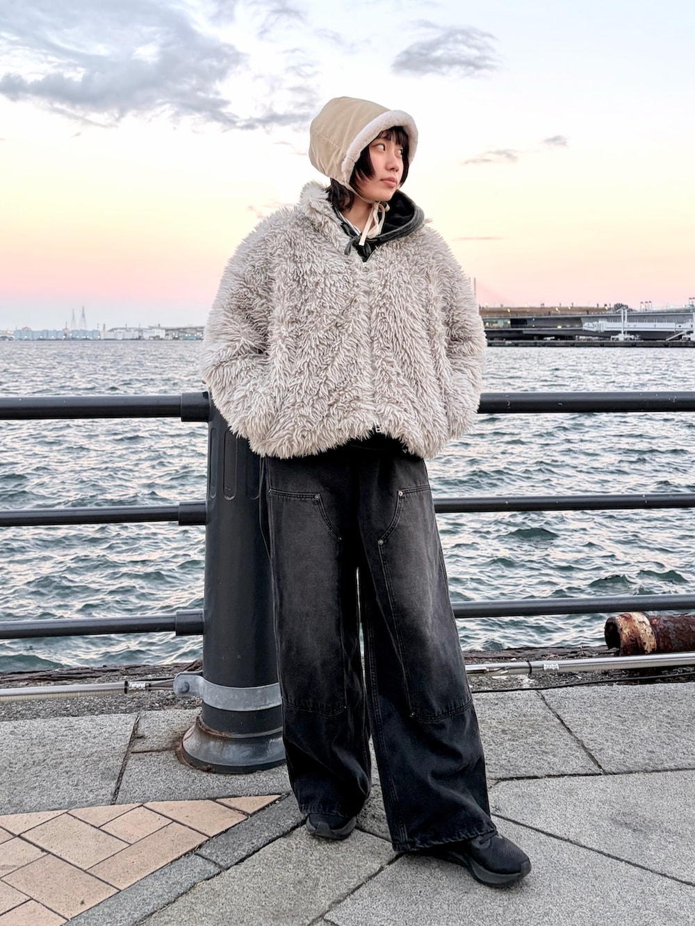 ブラック系のデニムパンツ、ブラック系のスニーカー、ホワイト系のハットを着用したレディースの冬コーディネートの2枚目の写真