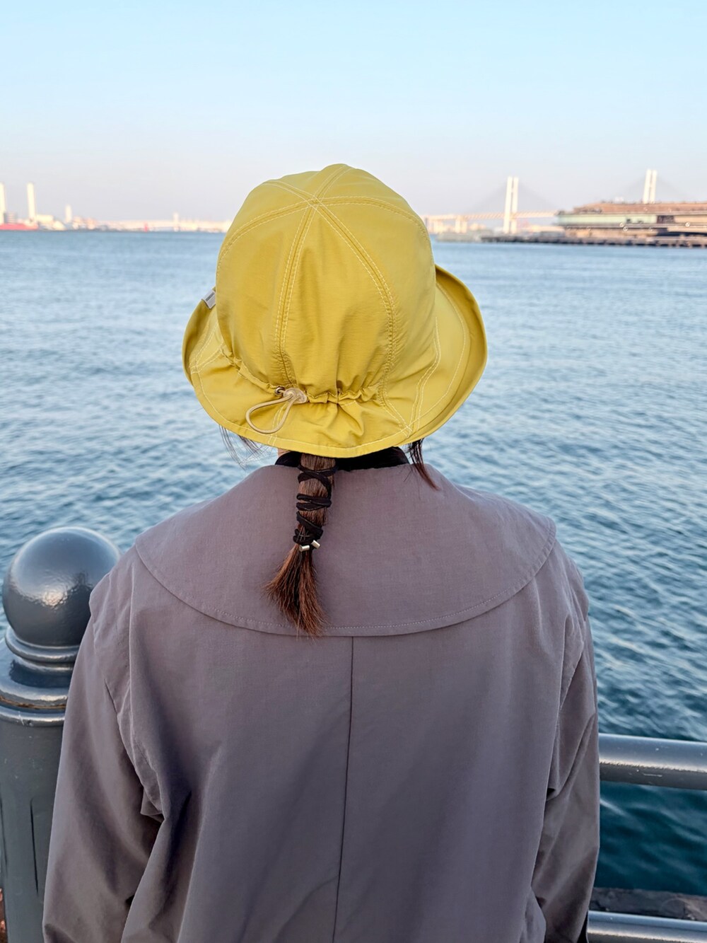 グレー系のトレンチコート、グリーン系のスカート、ブラック系のスニーカーを着用したレディースの冬コーディネートの6枚目の写真