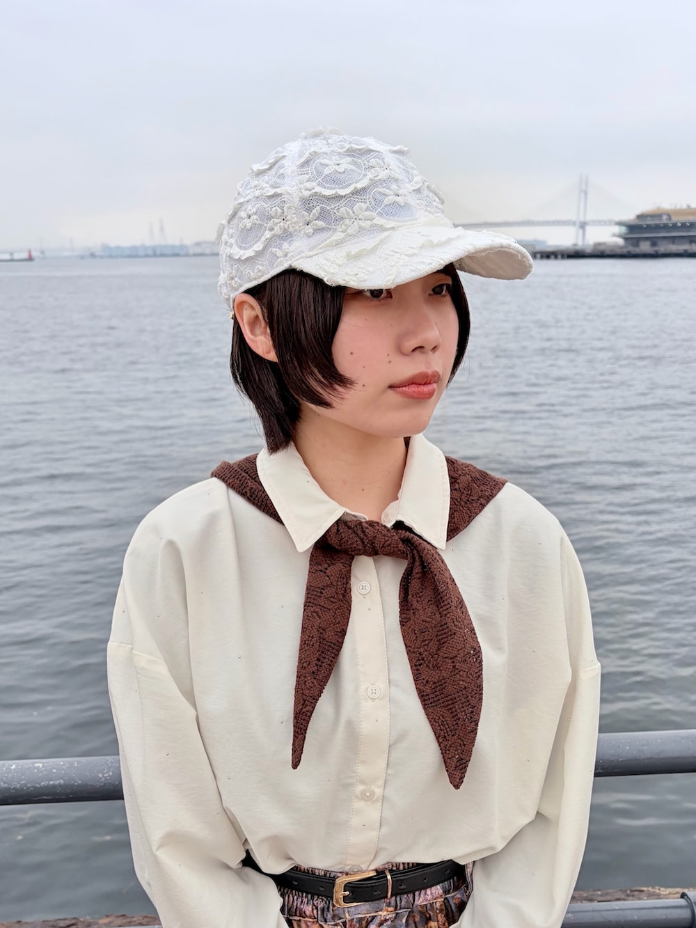 パープル系のパンツ、ブラック系のスニーカー、ホワイト系のキャップを着用したレディースの春コーディネートの4枚目の写真