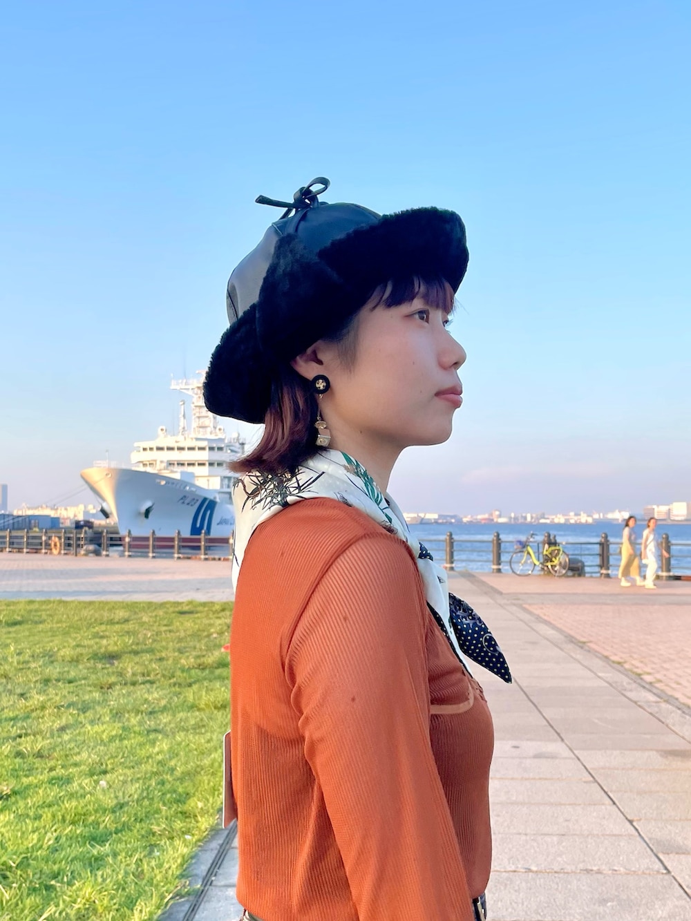 オレンジ系のTシャツ/カットソー、ブラウン系のデニムパンツ、ホワイト系のスニーカーを着用したレディースの秋コーディネートの5枚目の写真