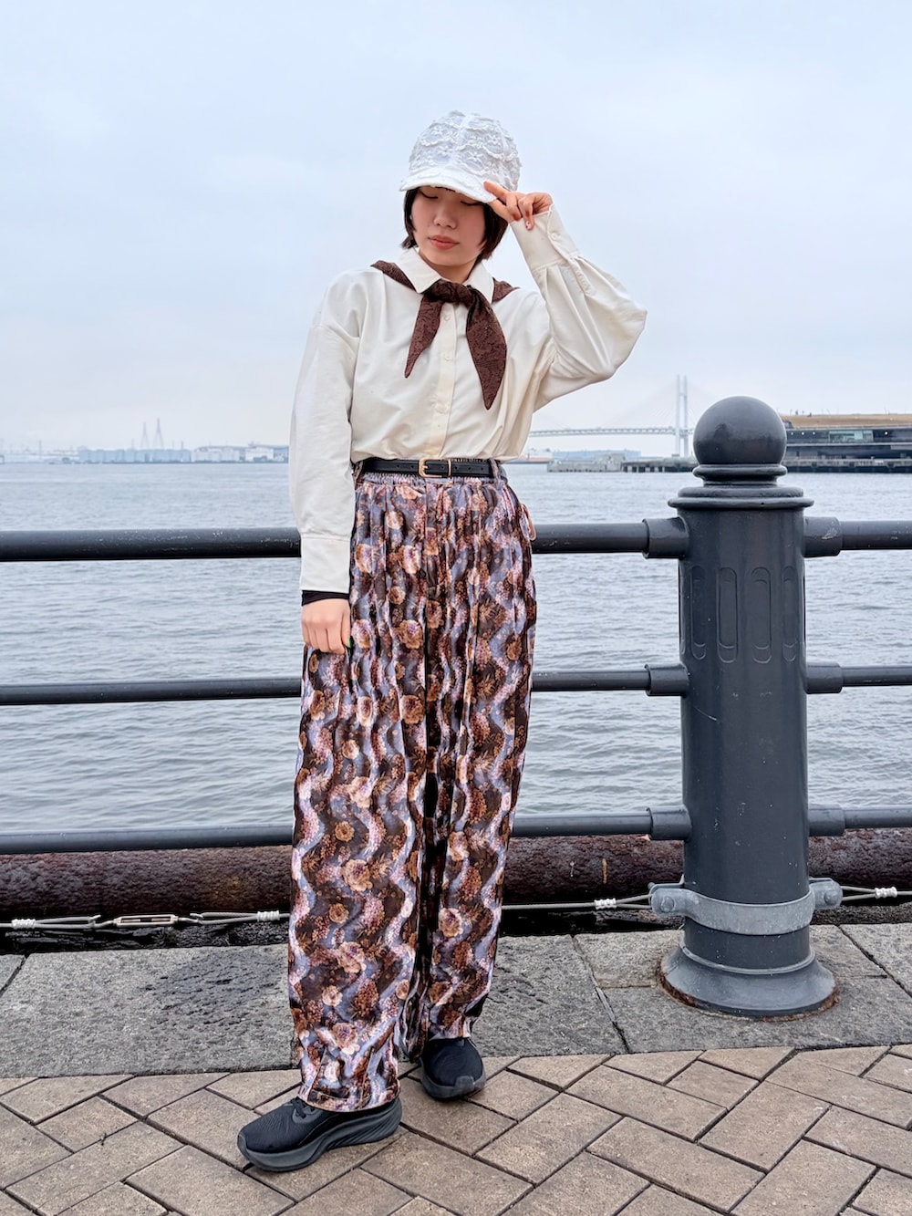 パープル系のパンツ、ブラック系のスニーカー、ホワイト系のキャップを着用したレディースの春コーディネートの2枚目の写真