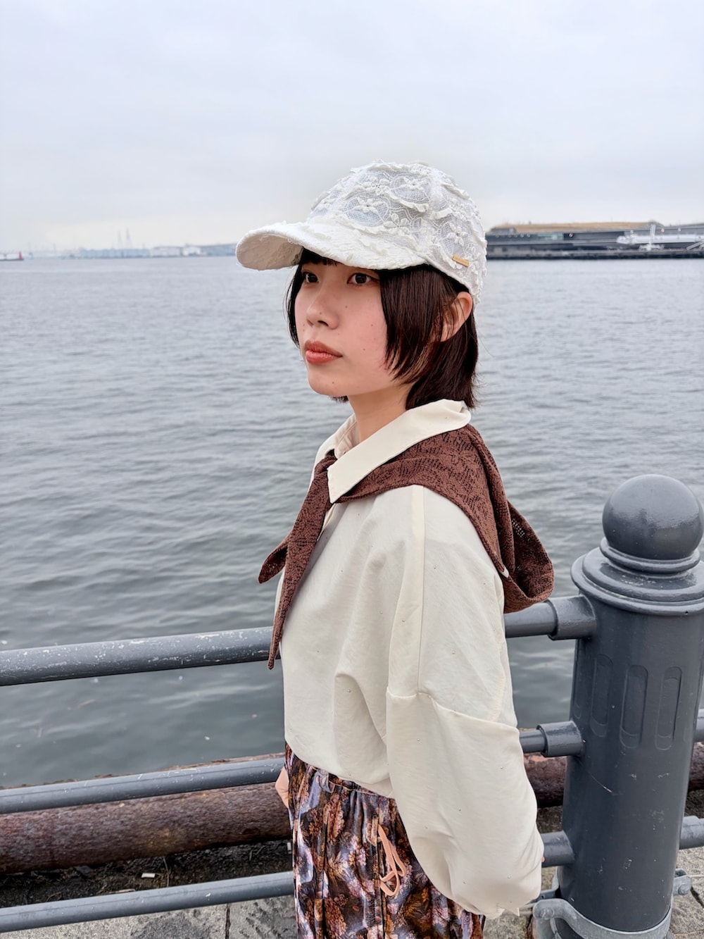 パープル系のパンツ、ブラック系のスニーカー、ホワイト系のキャップを着用したレディースの春コーディネートの5枚目の写真