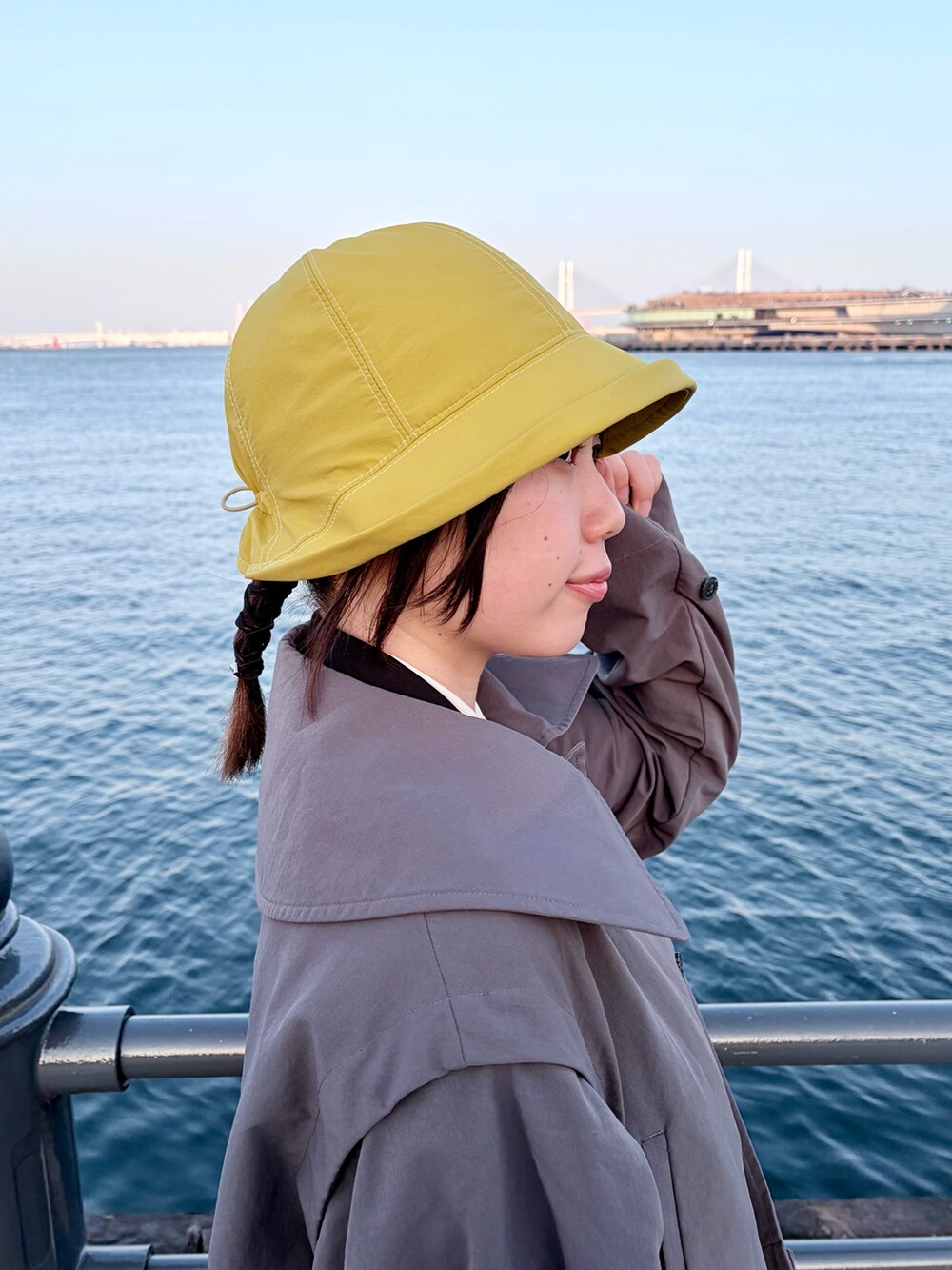 グレー系のトレンチコート、グリーン系のスカート、ブラック系のスニーカーを着用したレディースの冬コーディネートの4枚目の写真