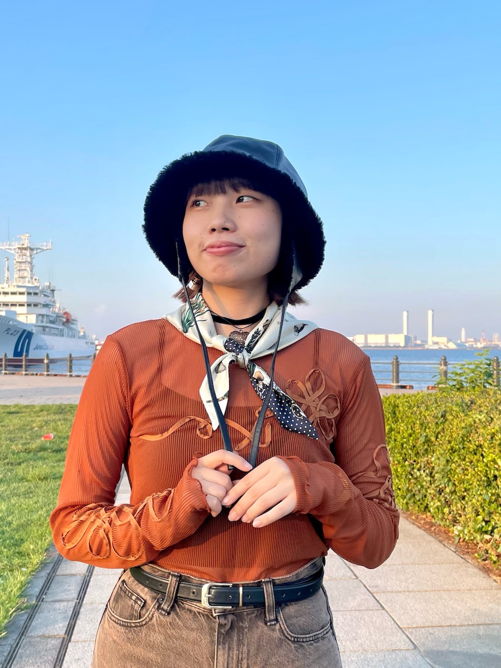 オレンジ系のTシャツ/カットソー、ブラウン系のデニムパンツ、ホワイト系のスニーカーを着用したレディースの秋コーディネートの4枚目の写真