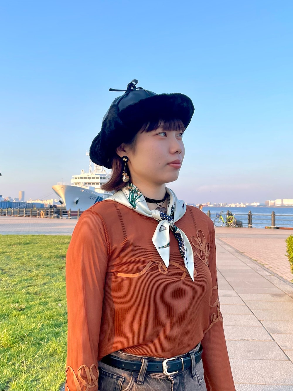 オレンジ系のTシャツ/カットソー、ブラウン系のデニムパンツ、ホワイト系のスニーカーを着用したレディースの秋コーディネートの3枚目の写真