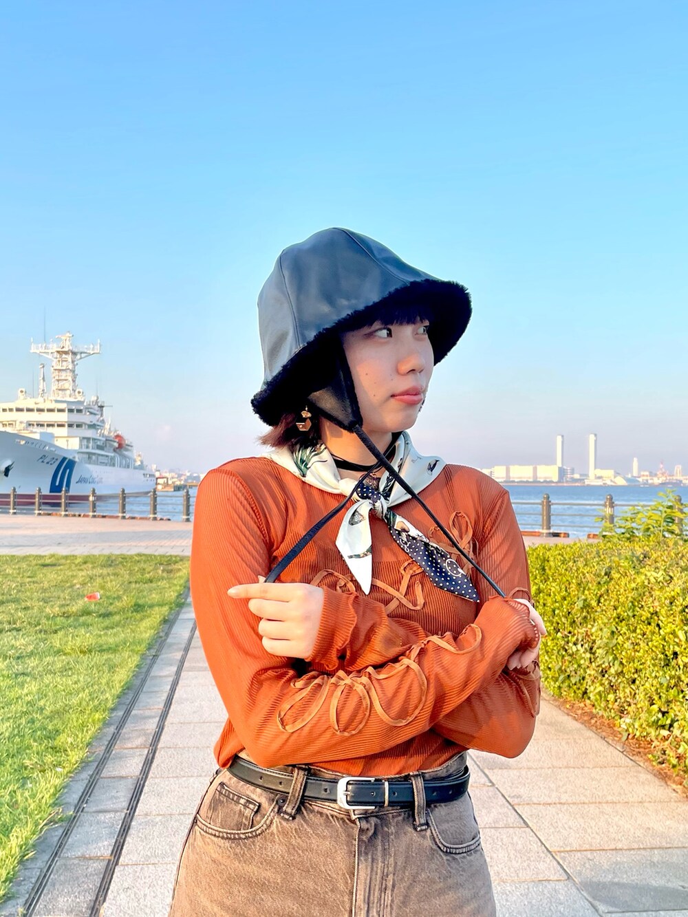 オレンジ系のTシャツ/カットソー、ブラウン系のデニムパンツ、ホワイト系のスニーカーを着用したレディースの秋コーディネートの8枚目の写真