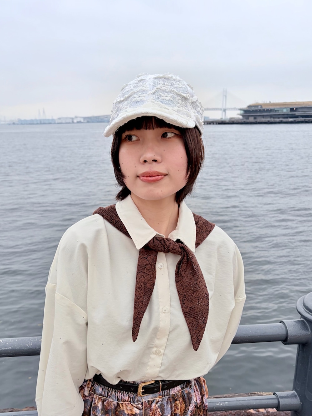 パープル系のパンツ、ブラック系のスニーカー、ホワイト系のキャップを着用したレディースの春コーディネートの3枚目の写真