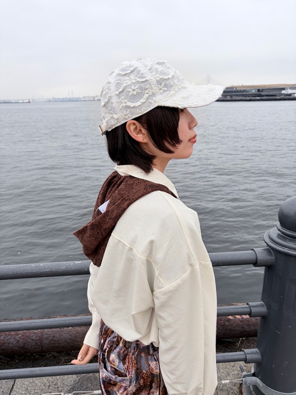 パープル系のパンツ、ブラック系のスニーカー、ホワイト系のキャップを着用したレディースの春コーディネートの7枚目の写真