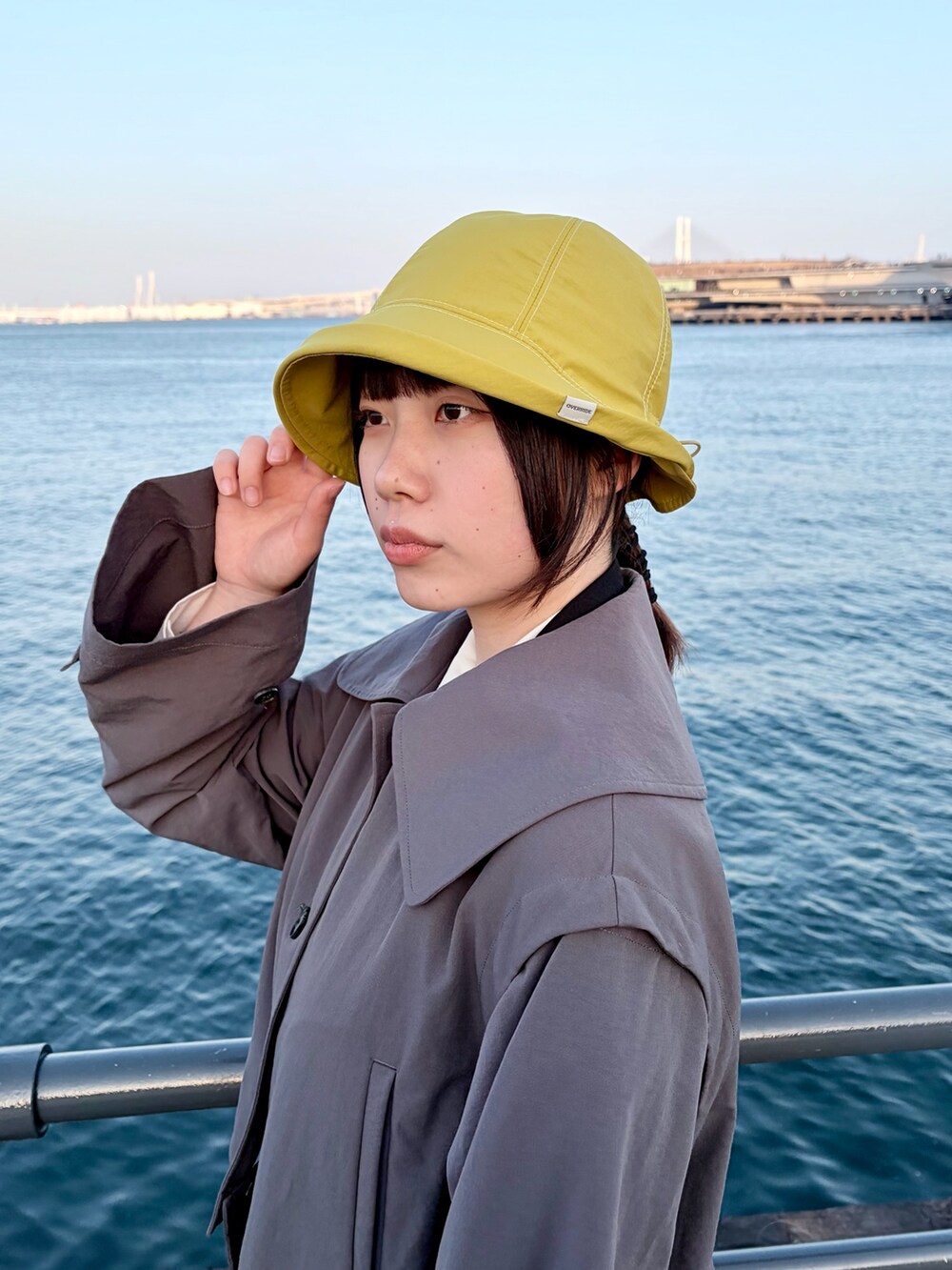 グレー系のトレンチコート、グリーン系のスカート、ブラック系のスニーカーを着用したレディースの冬コーディネートの3枚目の写真