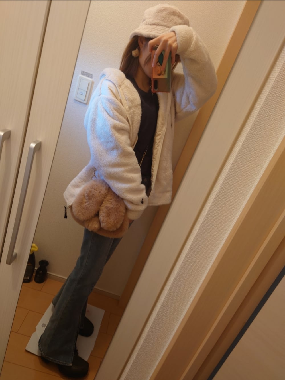 ホワイト系のパーカー、ブルー系のデニムパンツ、ベージュ系のショルダーバッグを着用したレディースの秋コーディネートの3枚目の写真