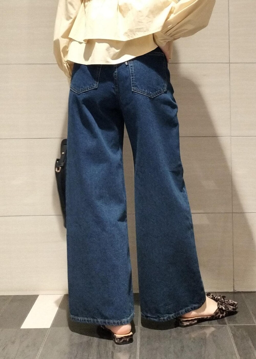 その他のサンダル、ブラック系のショルダーバッグ、ブルー系のデニムパンツを着用したレディースの秋コーディネートの8枚目の写真