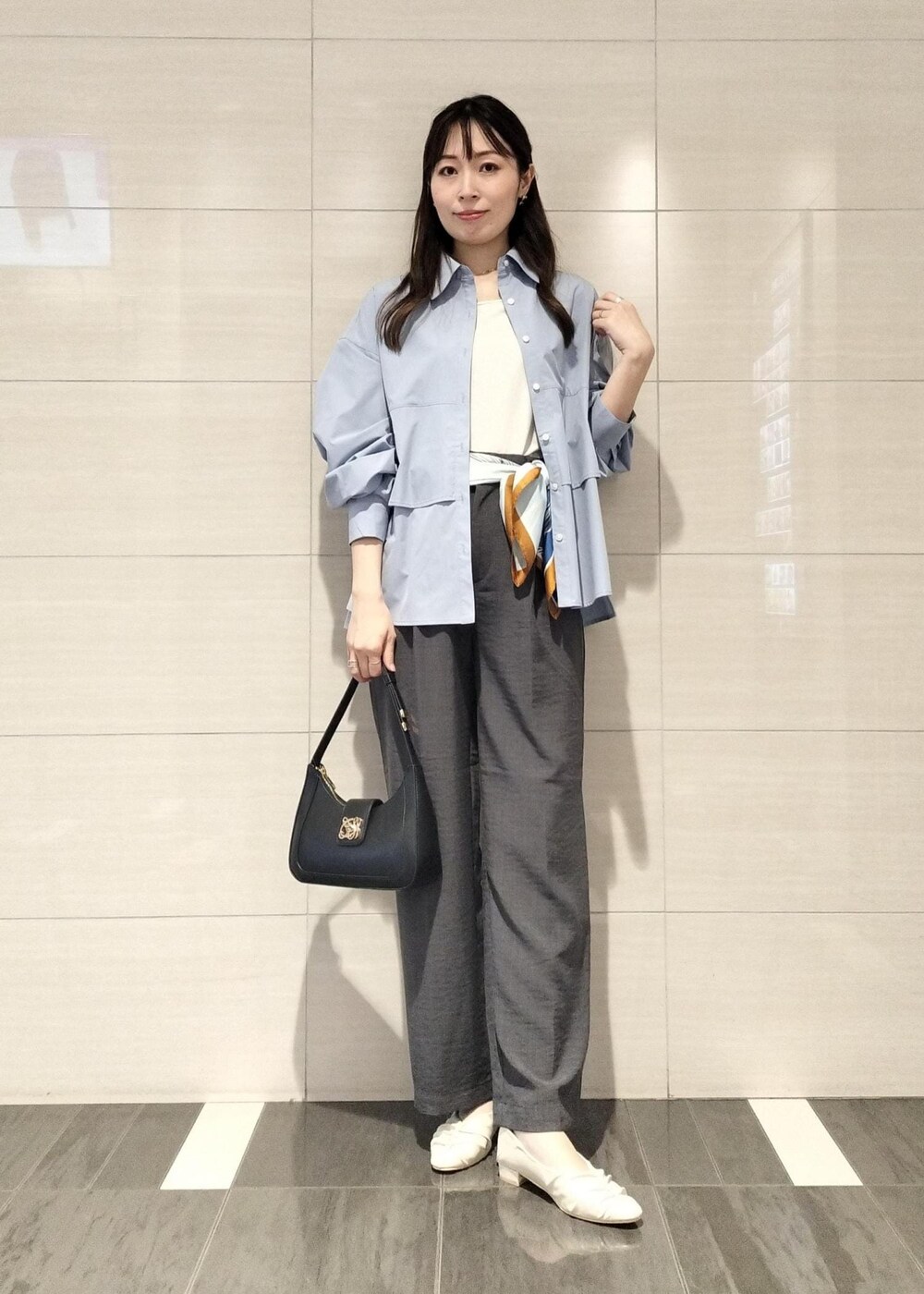 ブラック系のハンドバッグ、ホワイト系のキャミソール、グレー系のスラックスを着用したレディースの秋コーディネートの2枚目の写真