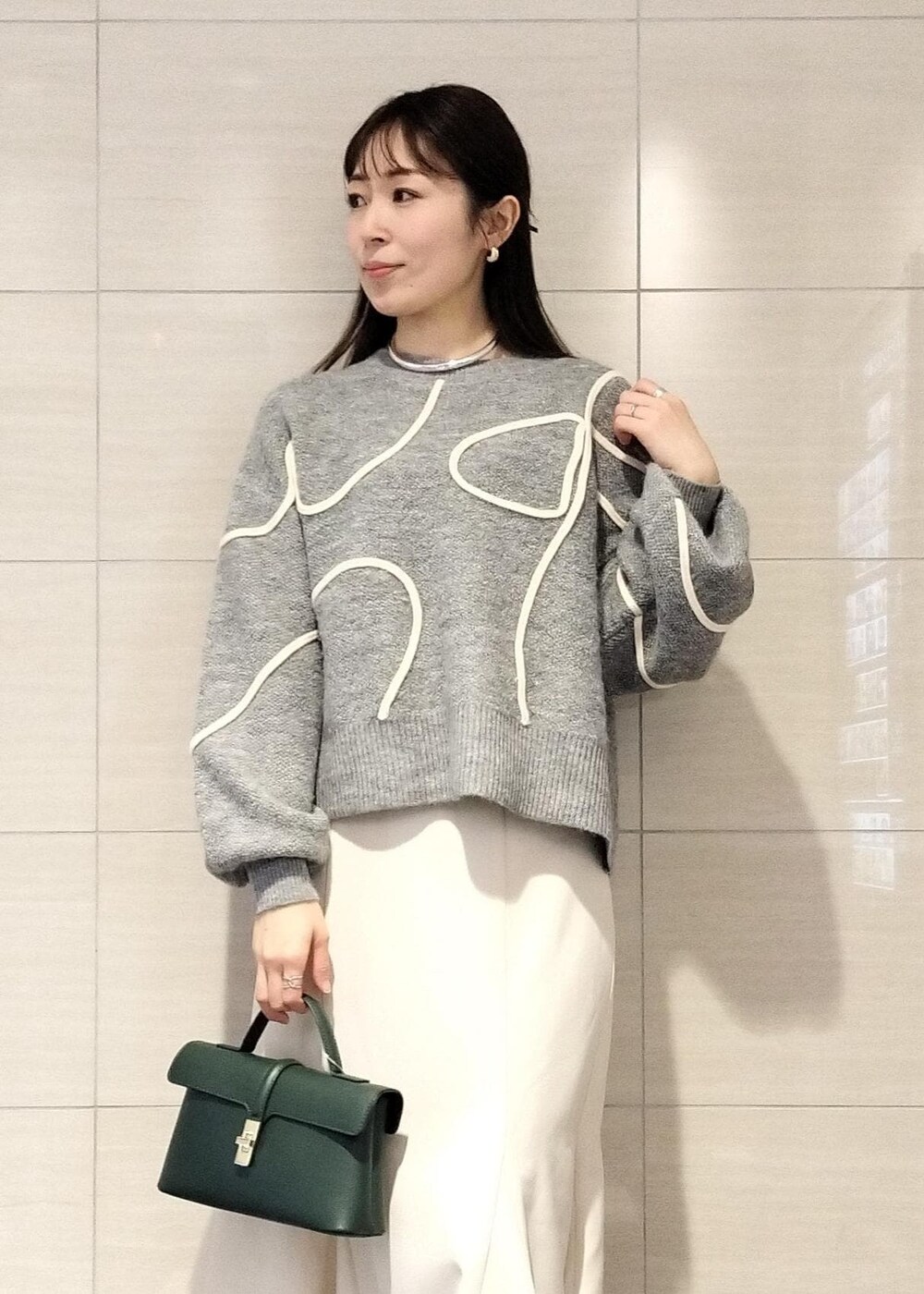 ホワイト系のブーツ、ホワイト系のスカート、グレー系のニット/セーターを着用したレディースの冬コーディネートの3枚目の写真
