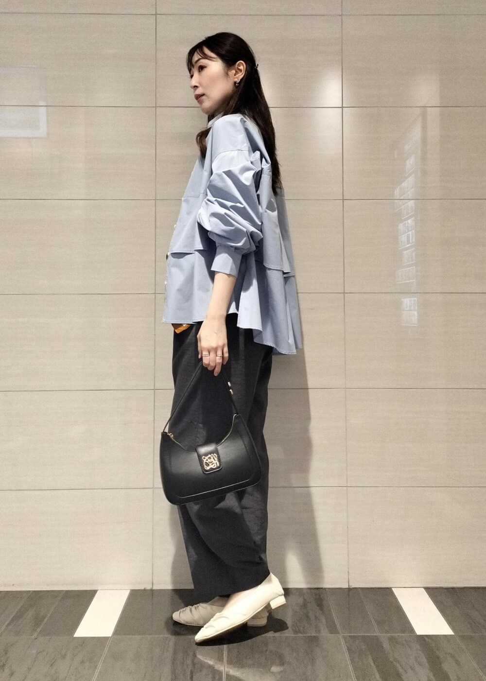 ブラック系のハンドバッグ、ホワイト系のキャミソール、グレー系のスラックスを着用したレディースの秋コーディネートの3枚目の写真