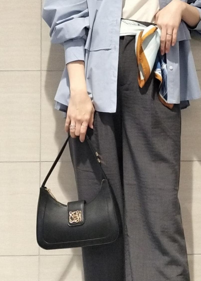 ブラック系のハンドバッグ、ホワイト系のキャミソール、グレー系のスラックスを着用したレディースの秋コーディネートの7枚目の写真