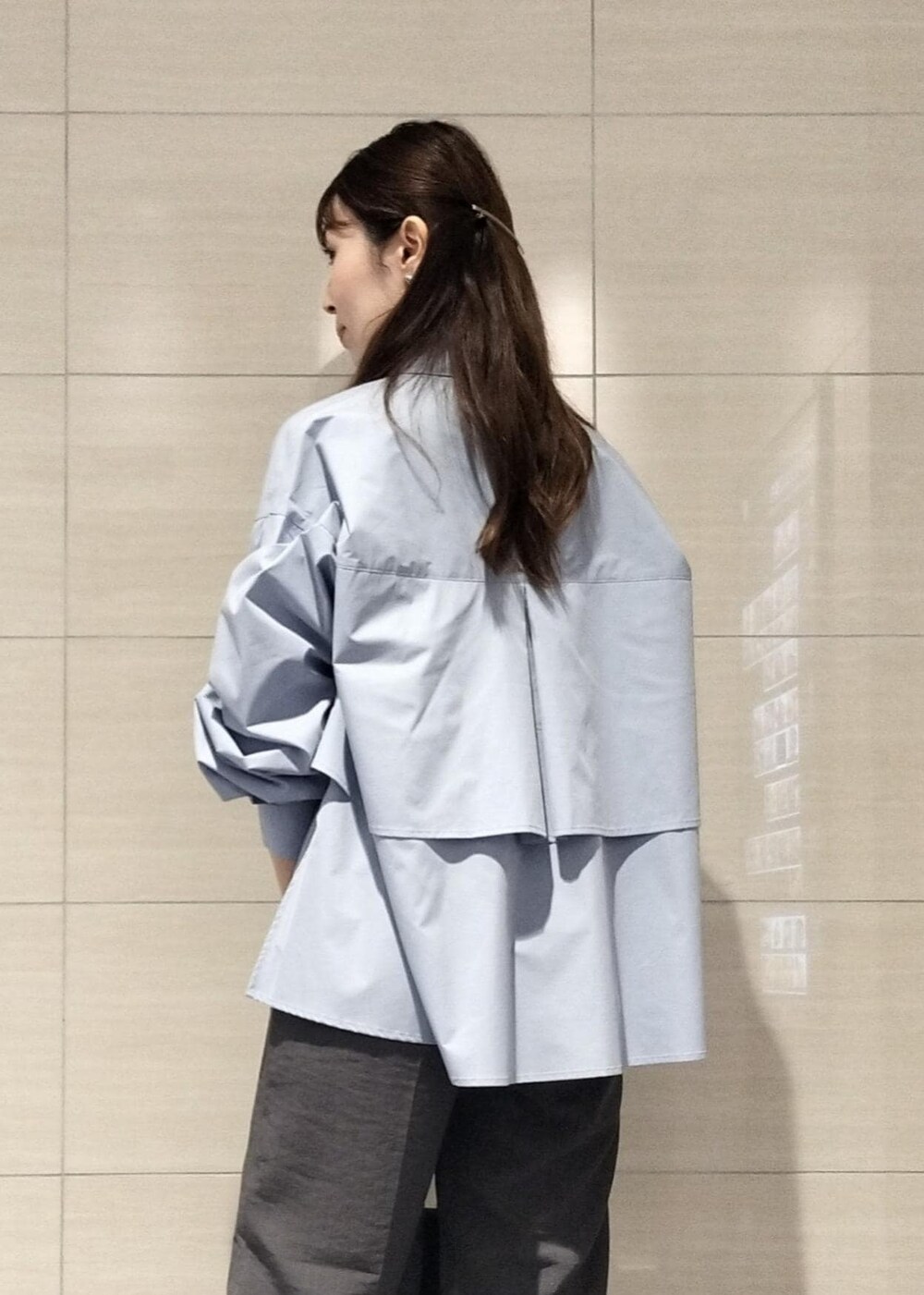 ブラック系のハンドバッグ、ホワイト系のキャミソール、グレー系のスラックスを着用したレディースの秋コーディネートの5枚目の写真