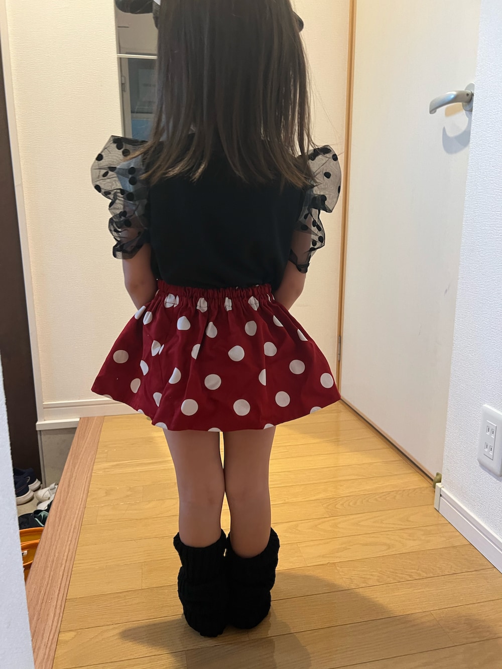 ブラック系のトップス、レッド系のスカート、ブラック系のレッグウォーマーを着用したキッズの秋コーディネートの2枚目の写真