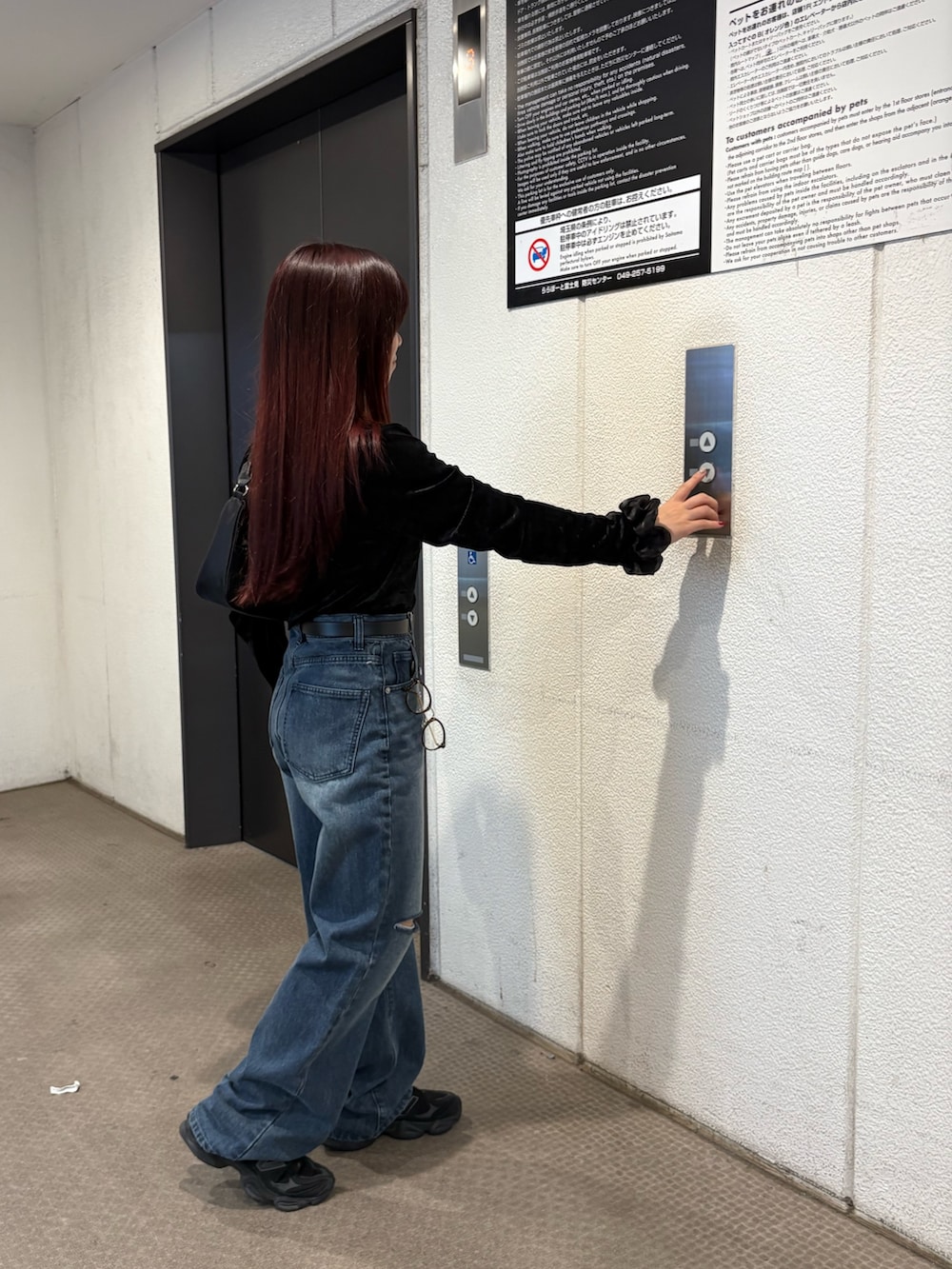 ブルー系のデニムパンツ、ブラック系のハンドバッグ、ブラック系のTシャツ/カットソーを着用したレディースの秋コーディネートの4枚目の写真