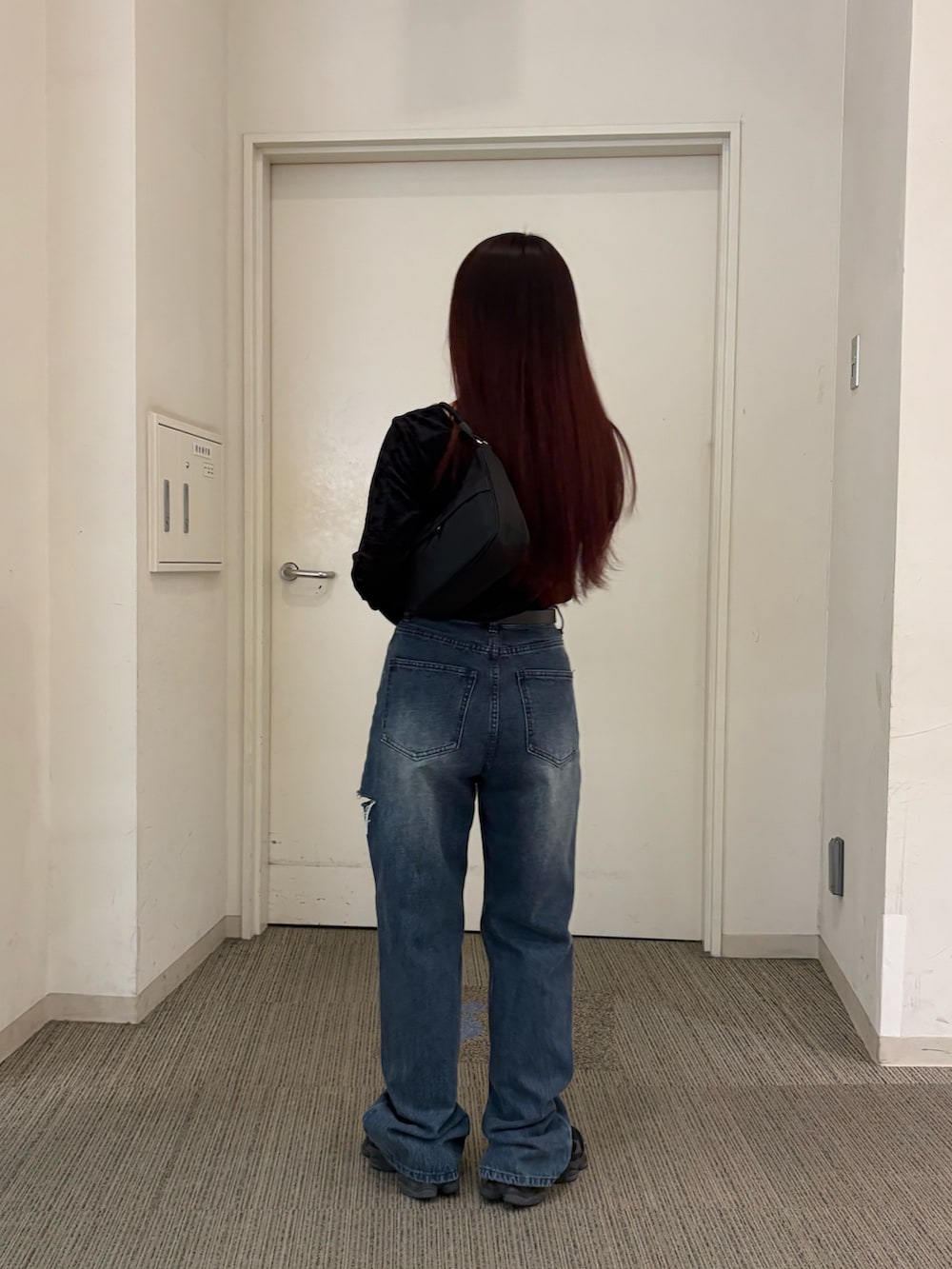 ブルー系のデニムパンツ、ブラック系のハンドバッグ、ブラック系のTシャツ/カットソーを着用したレディースの秋コーディネートの2枚目の写真