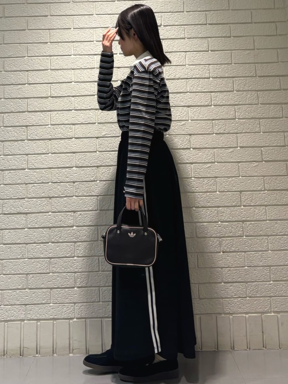 ブラック系のスカート、ブラック系のスニーカー、ブラウン系のショルダーバッグを着用したレディースの冬コーディネートの2枚目の写真