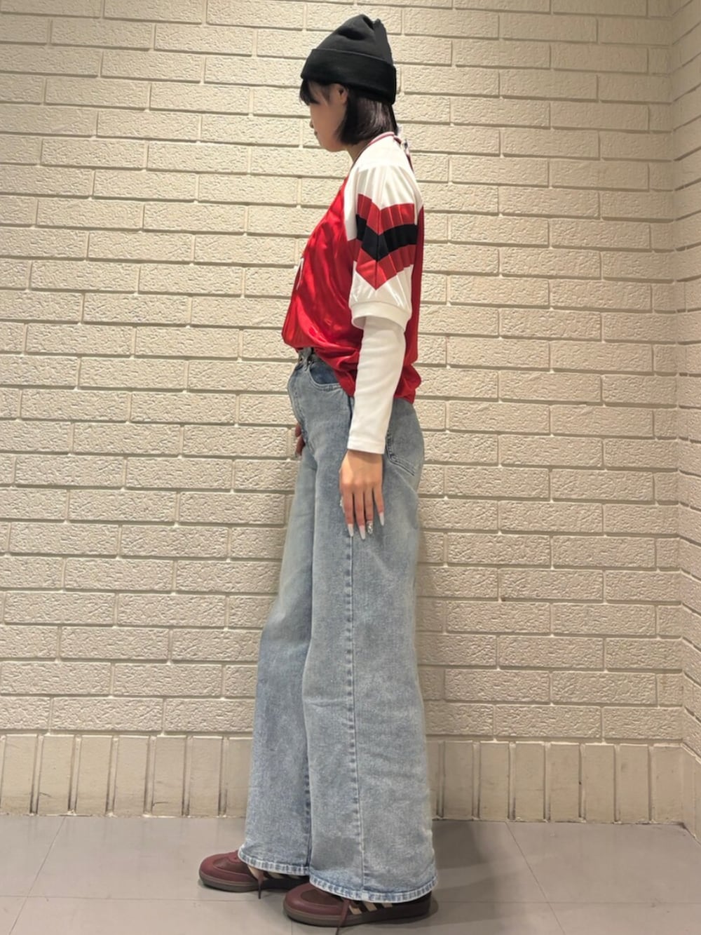 レッド系のトップス、ブラウン系のスニーカー、ブラック系のアクセサリーを着用したレディースの秋コーディネートの2枚目の写真