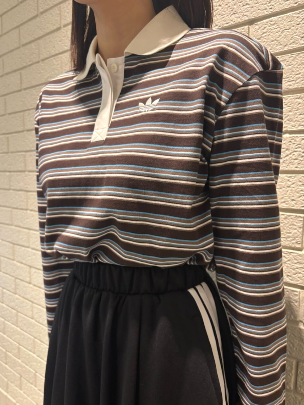 ブラック系のスカート、ブラック系のスニーカー、ブラウン系のショルダーバッグを着用したレディースの冬コーディネートの3枚目の写真