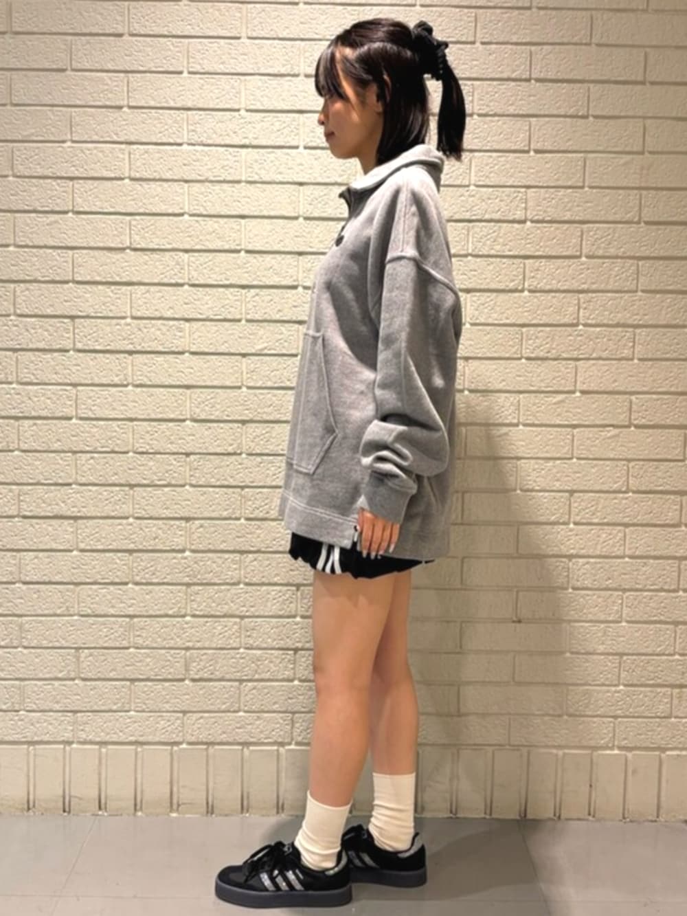 グレー系のパーカー、ブラック系のスカート、ブラック系のスニーカーを着用したレディースの冬コーディネートの2枚目の写真