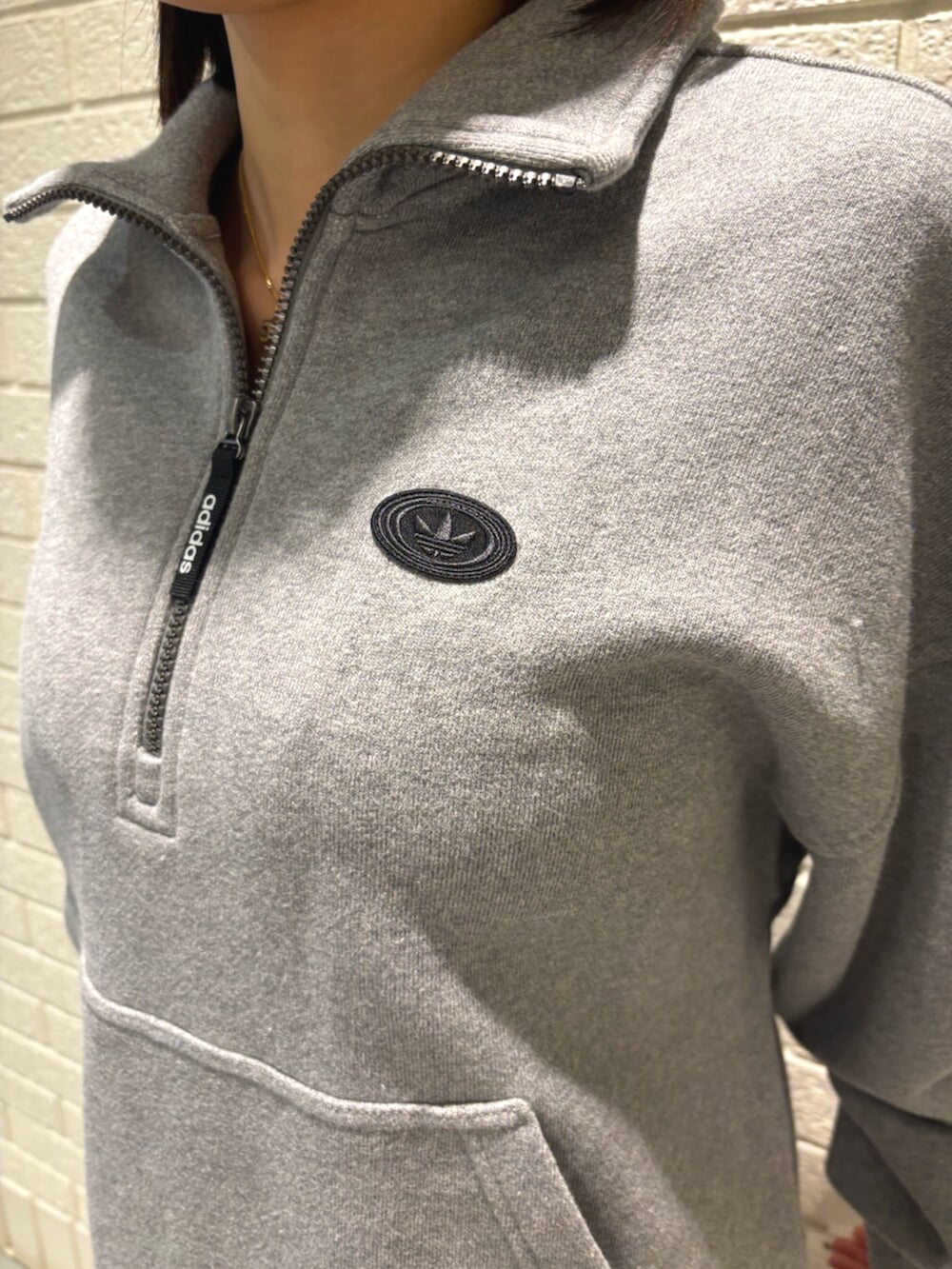 グレー系のパーカー、ブラック系のスカート、ブラック系のスニーカーを着用したレディースの冬コーディネートの3枚目の写真