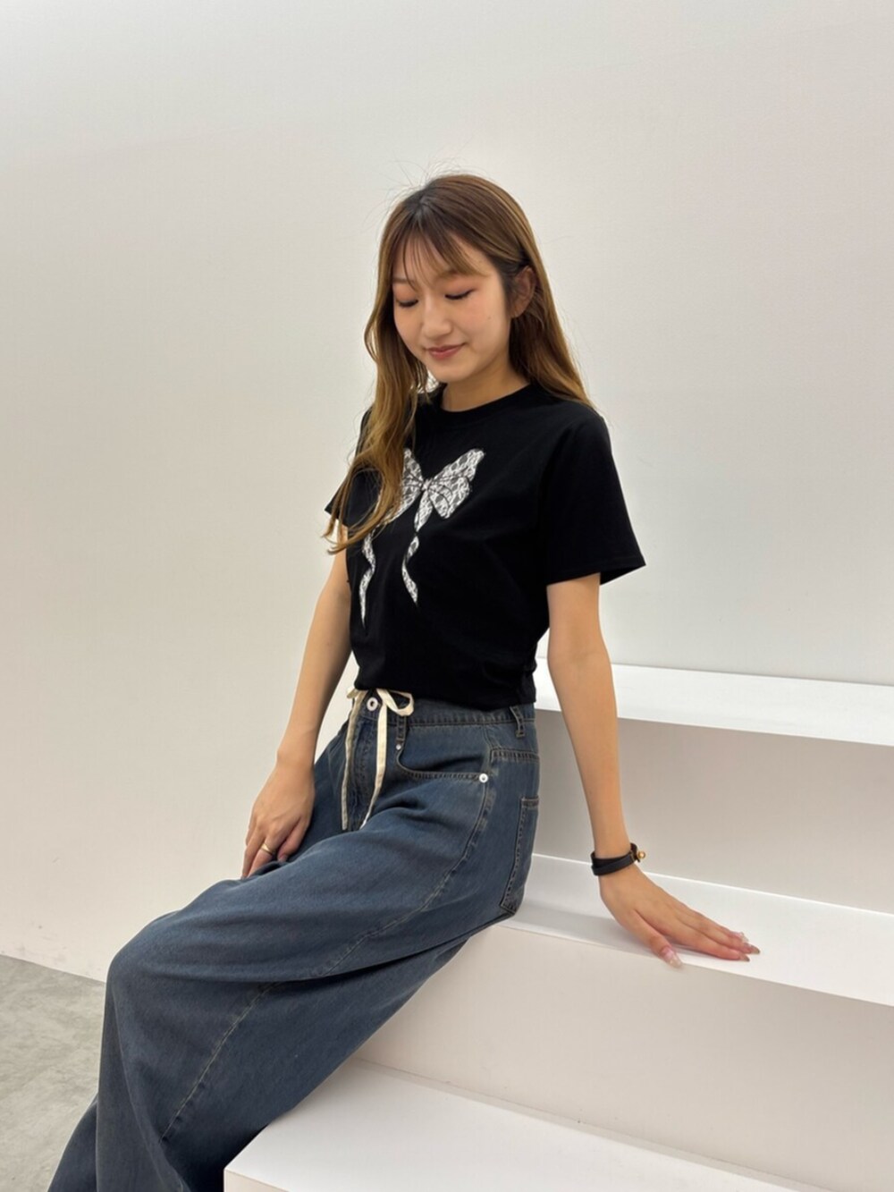 ブラック系のTシャツ/カットソー、ブルー系のデニムパンツ、ホワイト系のサンダルを着用したレディースの夏コーディネートの4枚目の写真