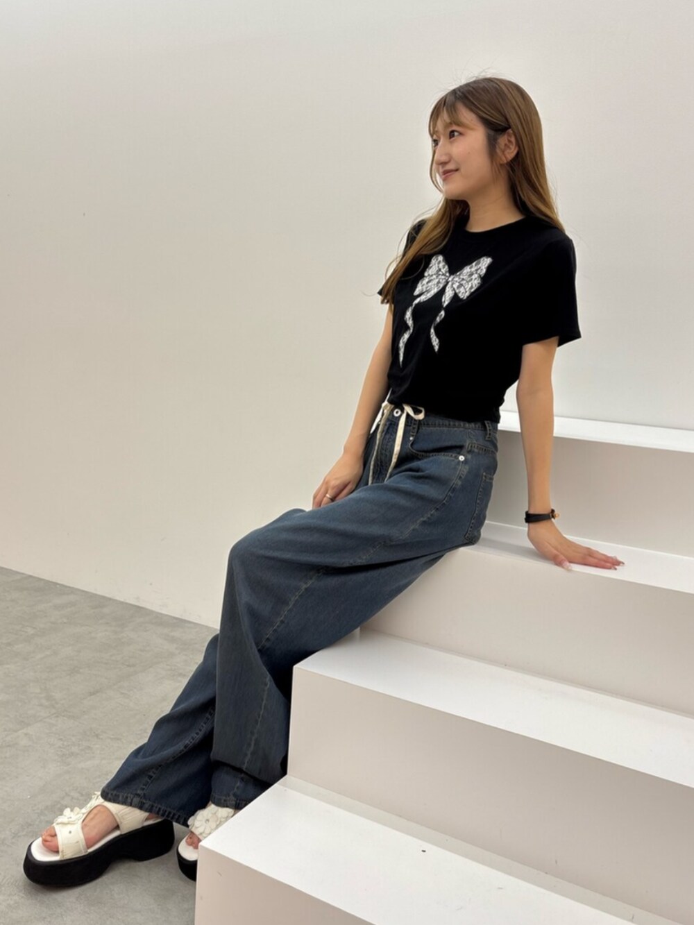 ブラック系のTシャツ/カットソー、ブルー系のデニムパンツ、ホワイト系のサンダルを着用したレディースの夏コーディネートの3枚目の写真