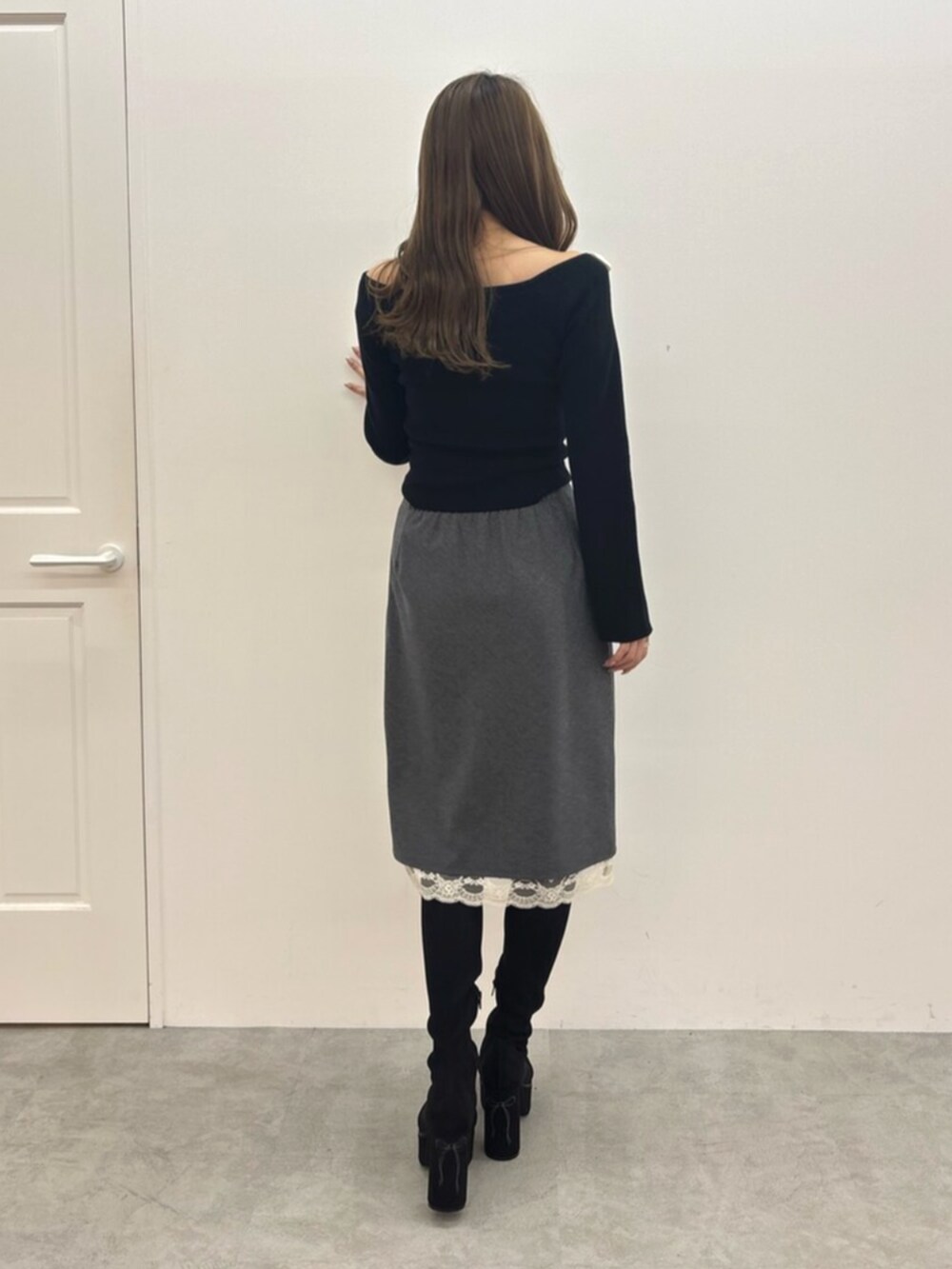 ブラック系のブーツ、ブラック系のニット/セーター、グレー系のスカートを着用したレディースの秋コーディネートの4枚目の写真
