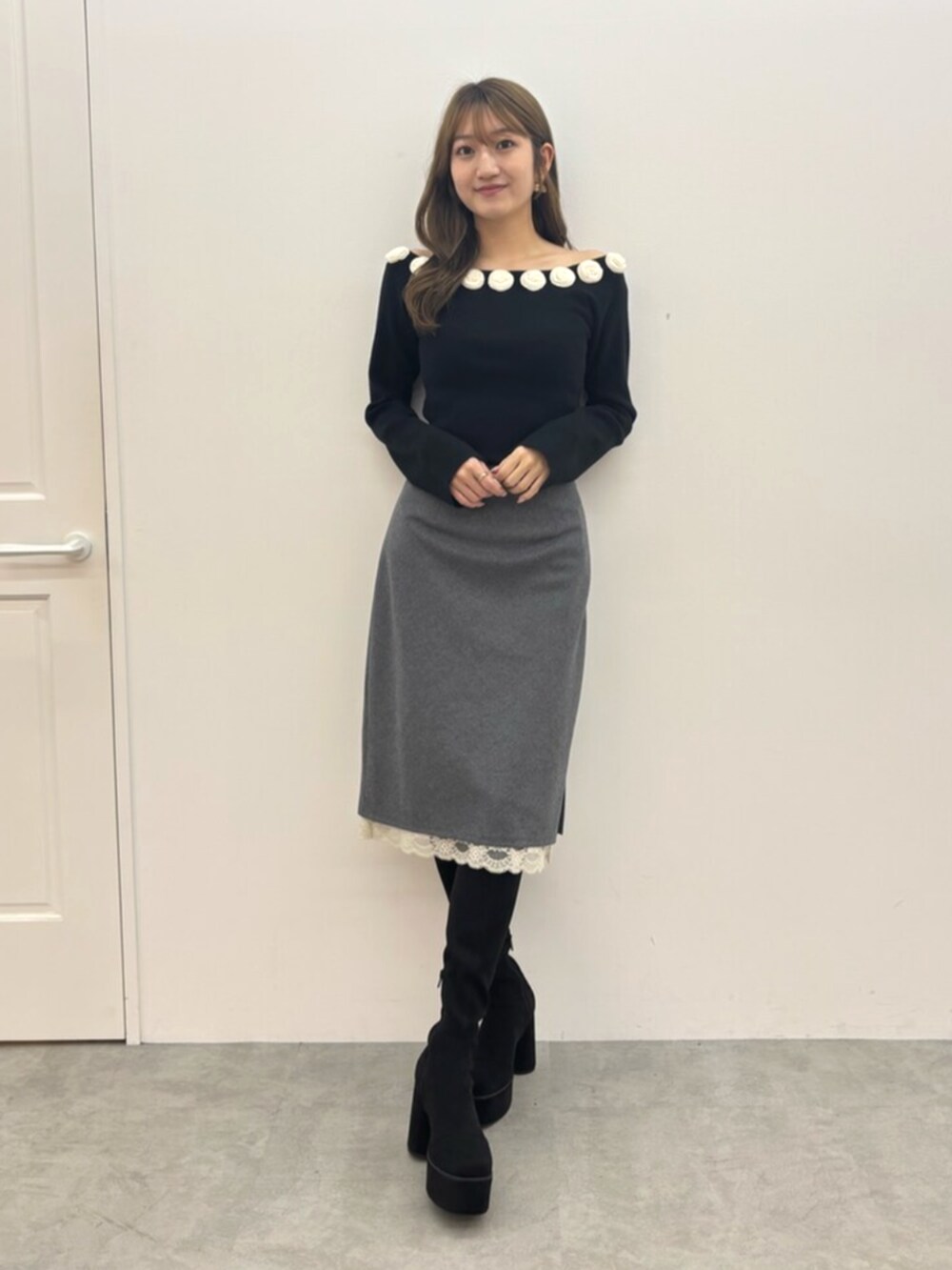 ブラック系のブーツ、ブラック系のニット/セーター、グレー系のスカートを着用したレディースの秋コーディネートの2枚目の写真