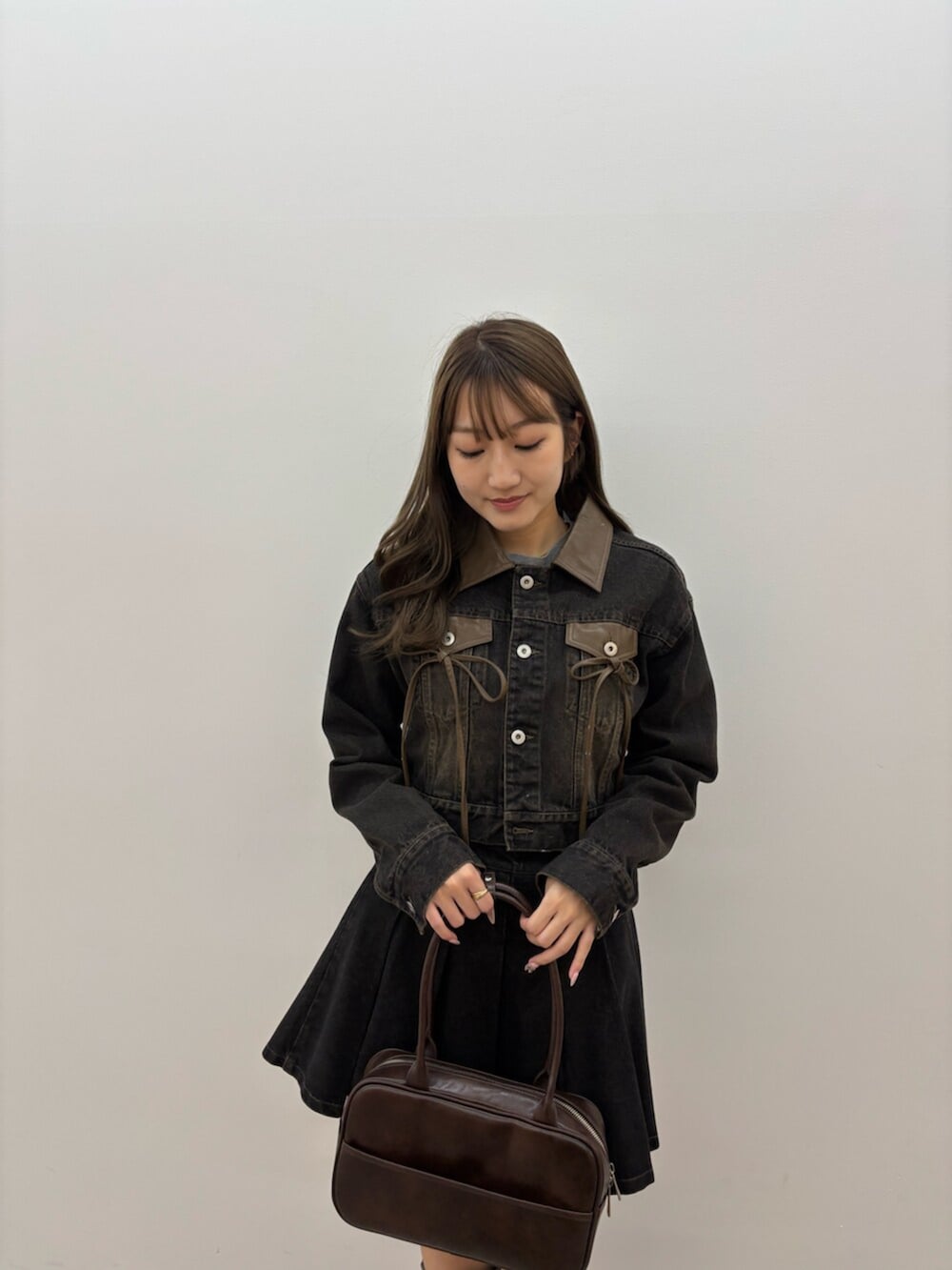 ブラウン系のブーツ、ブラック系のデニムジャケット、ブラック系のスカートを着用したレディースの秋コーディネートの3枚目の写真