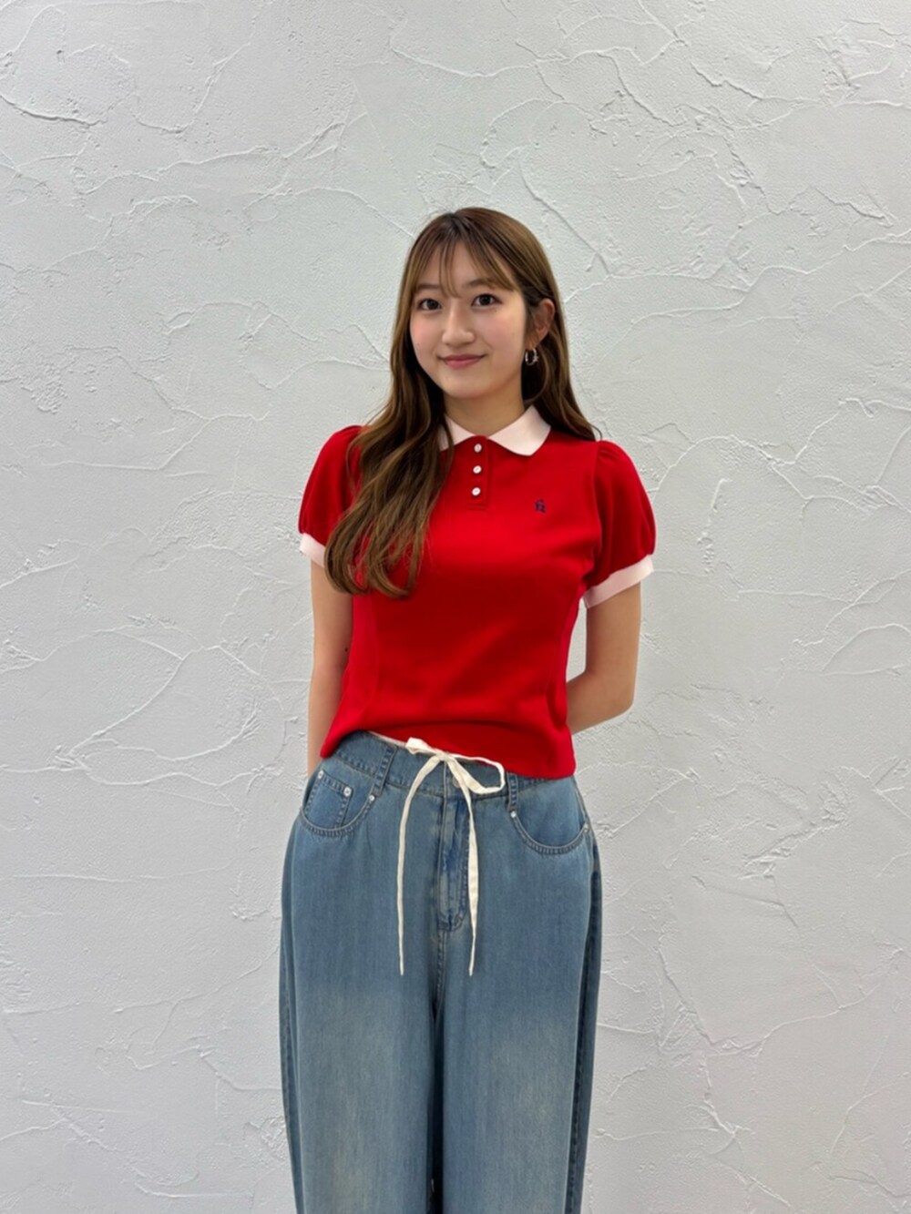 ブラック系のサンダル、ブルー系のデニムパンツ、レッド系のポロシャツを着用したレディースの夏コーディネートの2枚目の写真