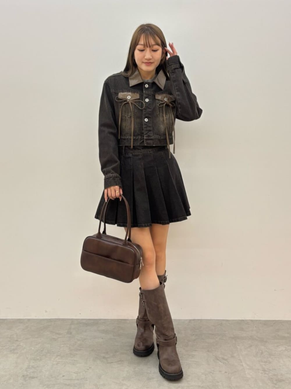 ブラウン系のブーツ、ブラック系のデニムジャケット、ブラック系のスカートを着用したレディースの秋コーディネートの2枚目の写真