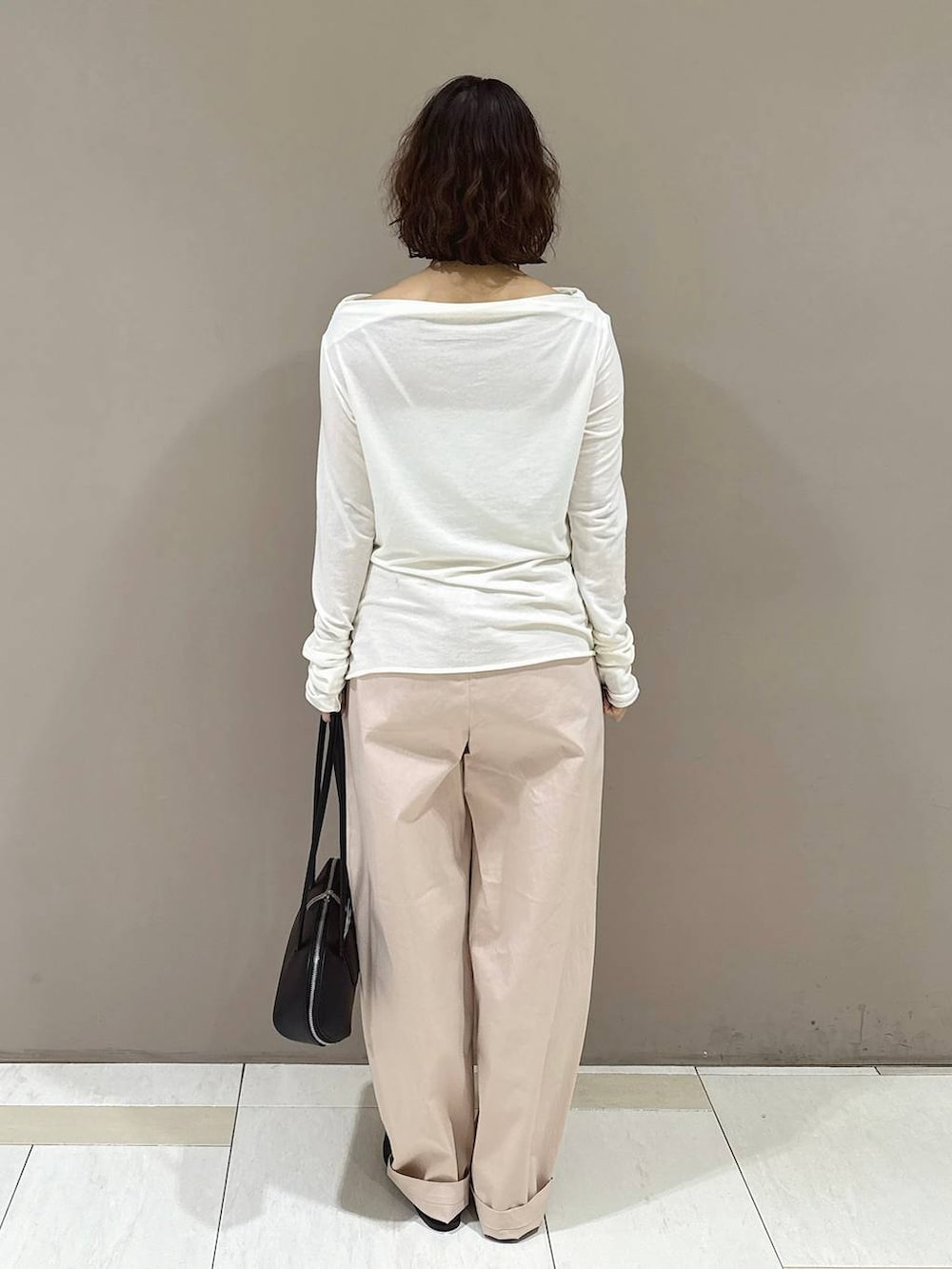 ブラック系のパンプス、ブラック系のハンドバッグ、ホワイト系のTシャツ/カットソーを着用したレディースの冬コーディネートの3枚目の写真