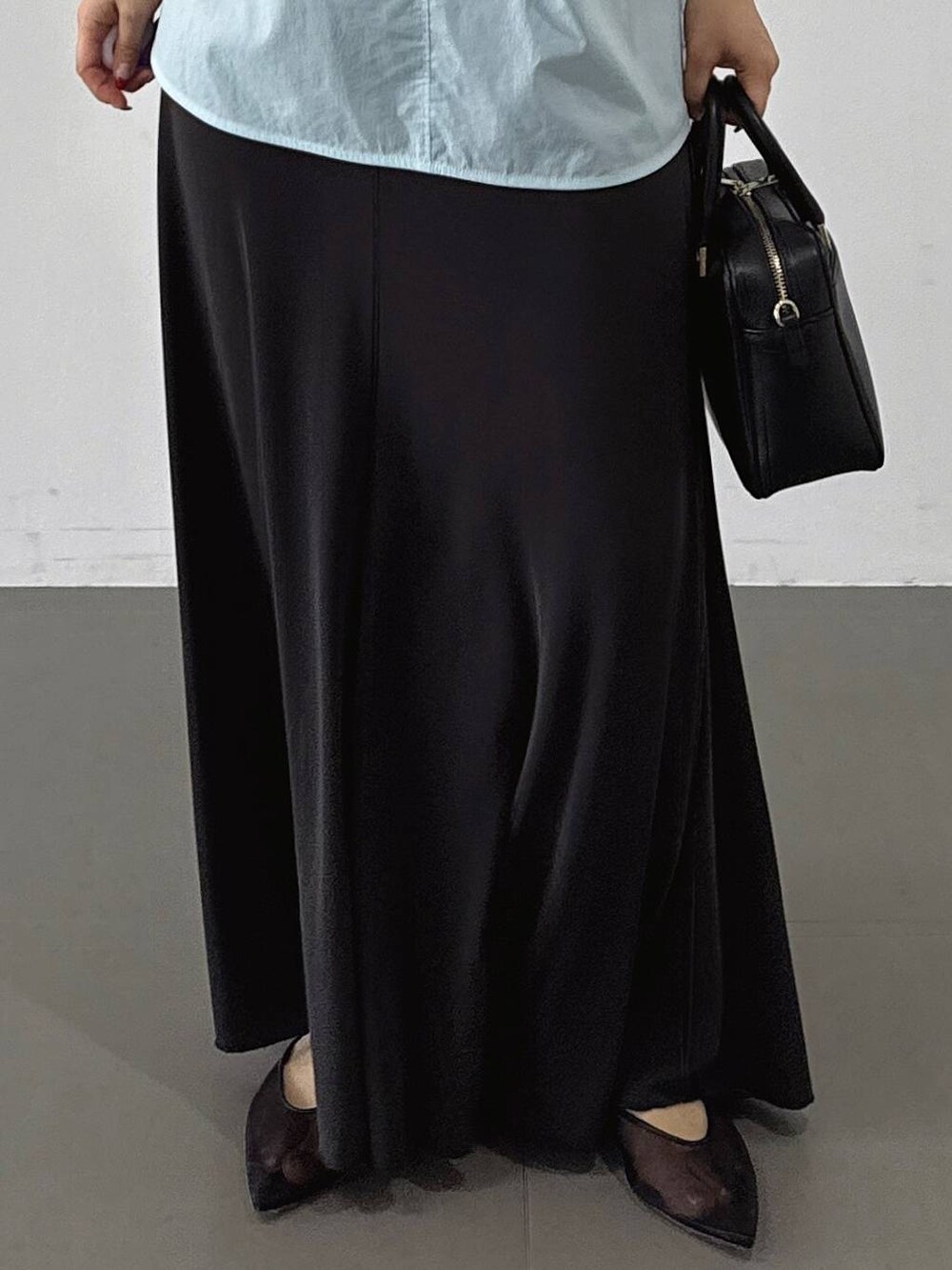 ブラック系のパンプス、ブラック系のボストンバッグ、グレー系のスカートを着用したレディースの春コーディネートの6枚目の写真