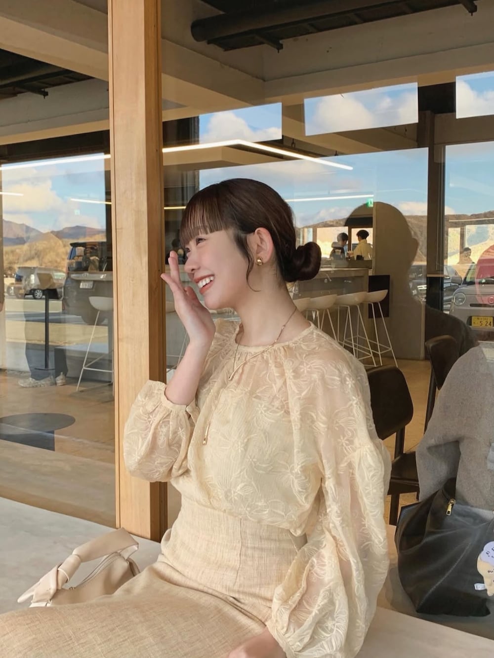 ベージュ系のトップス、ベージュ系のスカート、ホワイト系のバッグを着用したレディースの春コーディネートの2枚目の写真