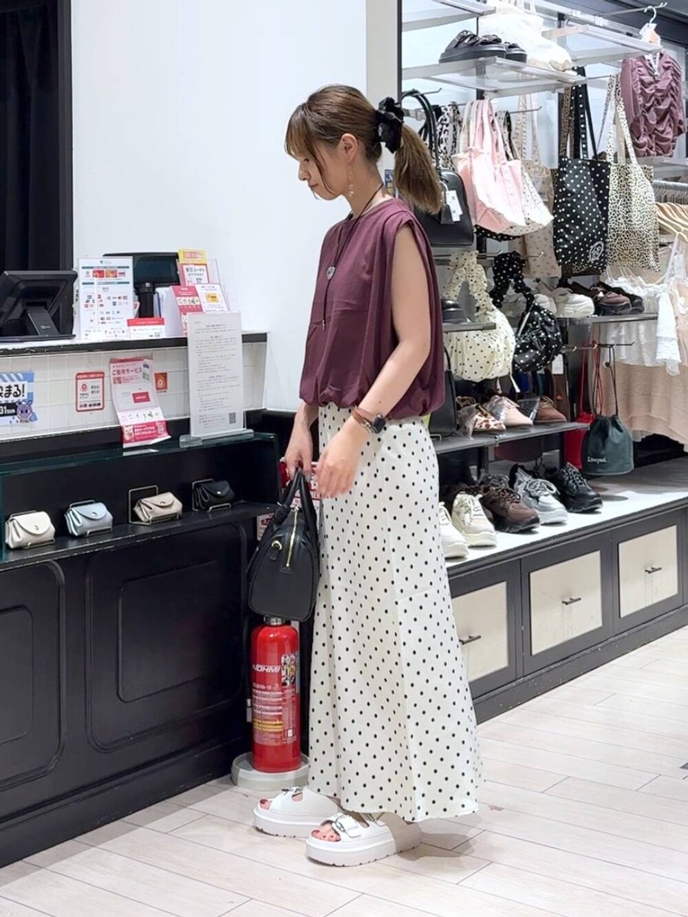 ホワイト系のスカート、ホワイト系のサンダル、ブラック系のショルダーバッグを着用したレディースの夏コーディネートの2枚目の写真