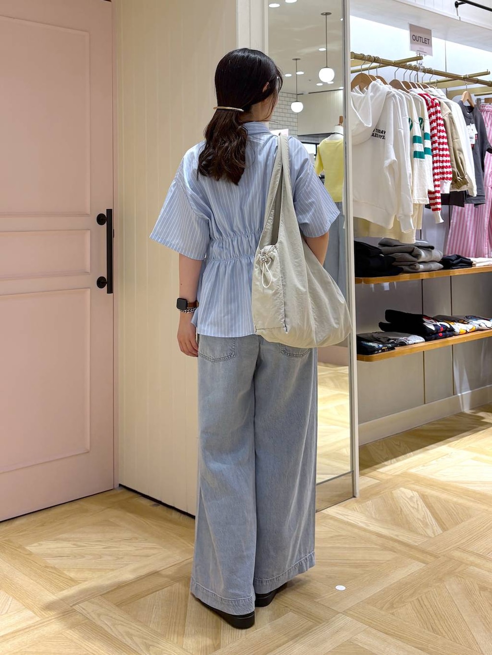 ブルー系のデニムパンツ、ブラック系のサンダル、ホワイト系のトートバッグを着用したレディースの春コーディネートの3枚目の写真