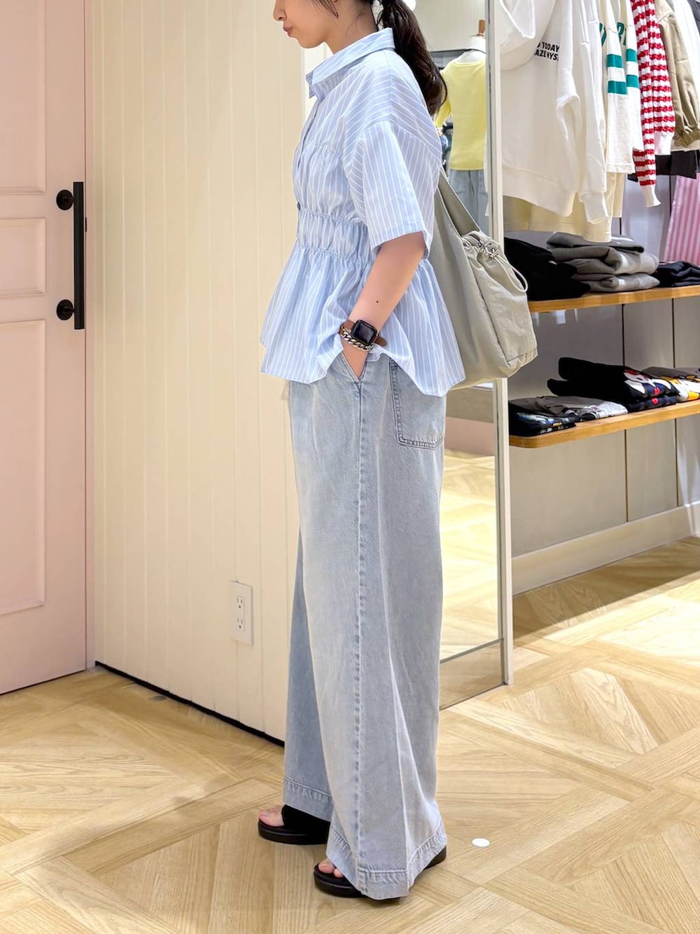 ブルー系のデニムパンツ、ブラック系のサンダル、ホワイト系のトートバッグを着用したレディースの春コーディネートの2枚目の写真