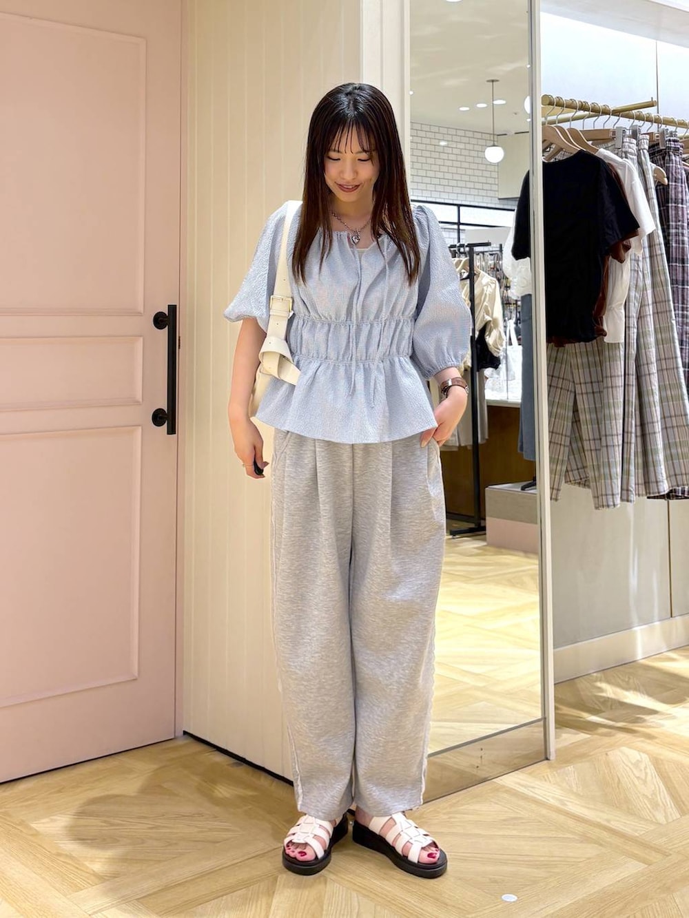 グレー系のスウェットパンツ、ホワイト系のサンダル、ホワイト系のショルダーバッグを着用したレディースの春コーディネートの4枚目の写真
