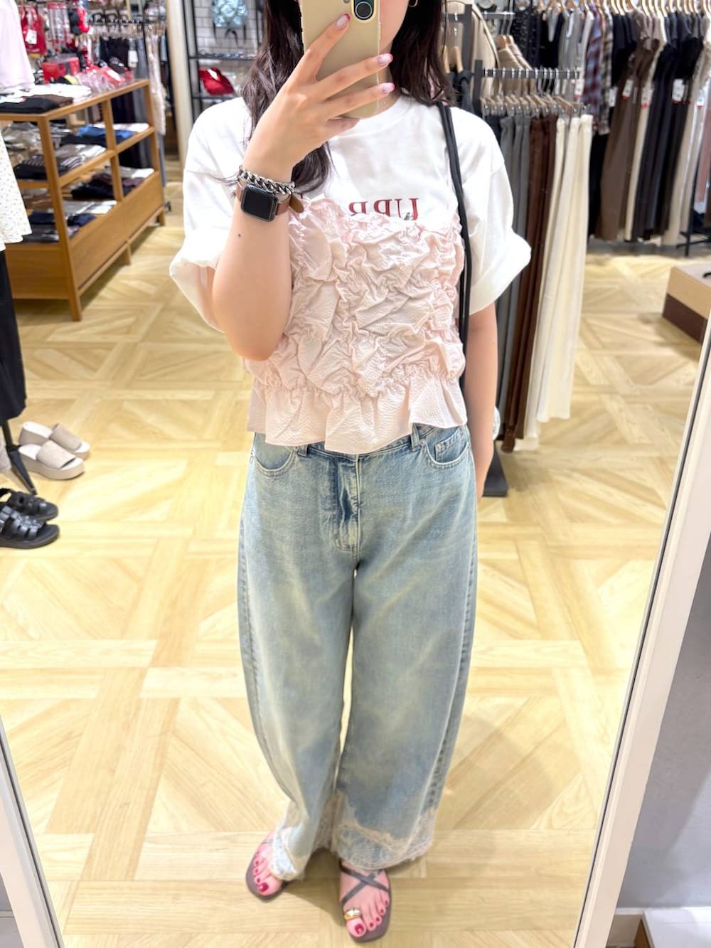ピンク系のベスト、ブルー系のデニムパンツ、ブラウン系のサンダルを着用したレディースの夏コーディネートの2枚目の写真
