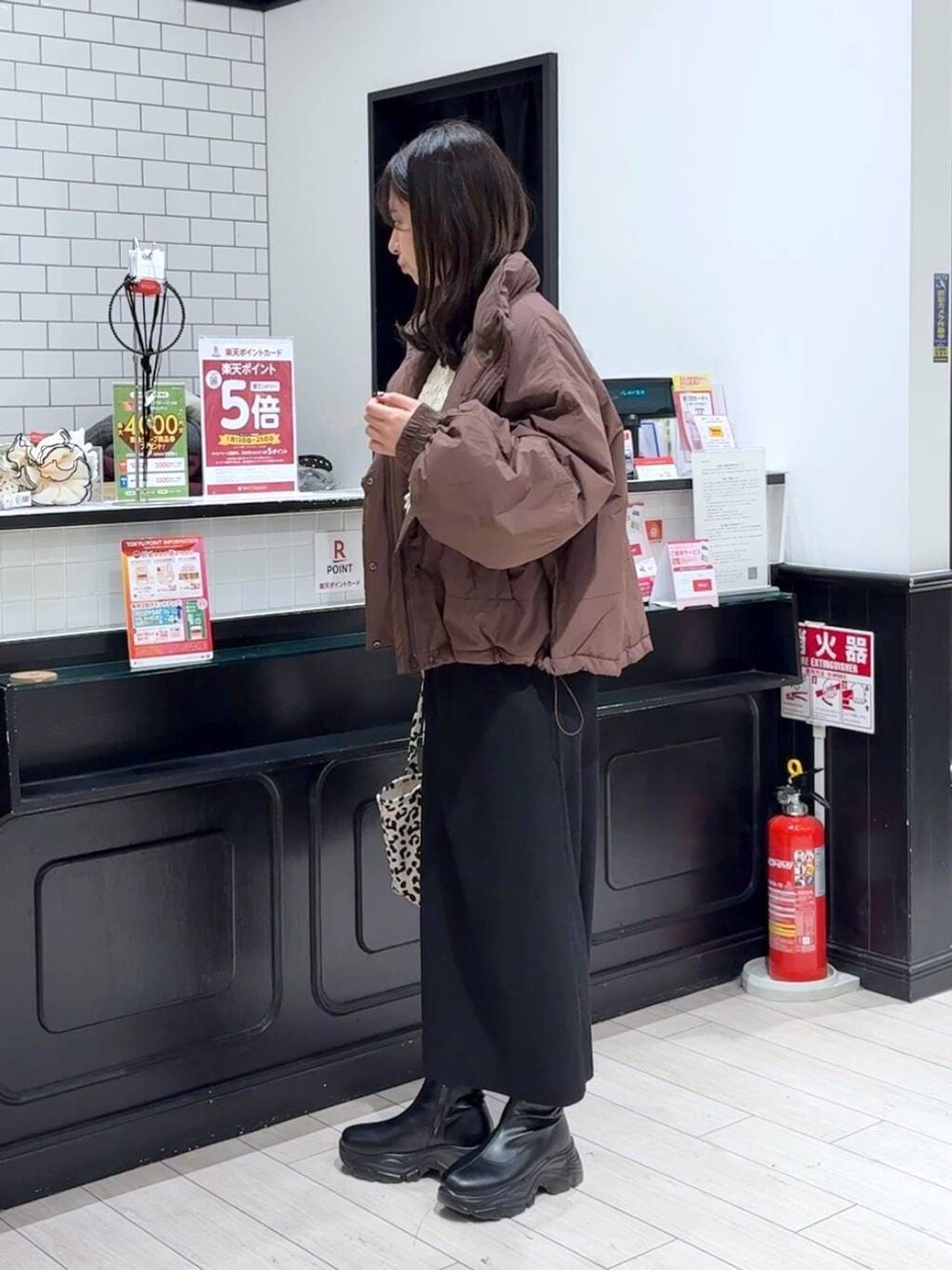 ブラック系のスカート、ブラウン系のその他アウター、ブラック系のブーツを着用したレディースの冬コーディネートの2枚目の写真