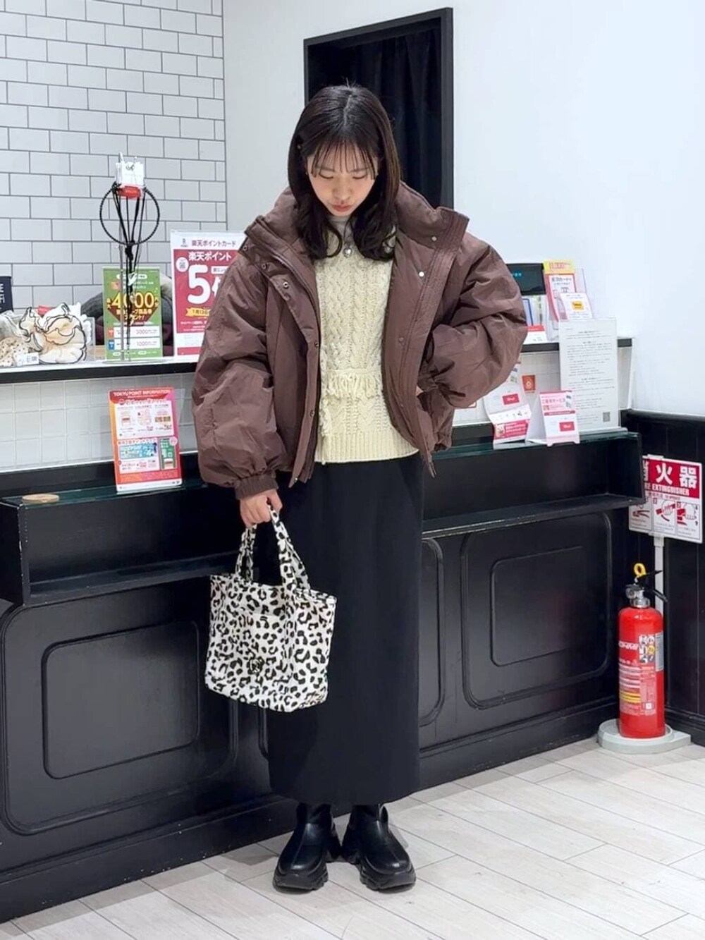 ブラック系のスカート、ブラウン系のその他アウター、ブラック系のブーツを着用したレディースの冬コーディネートの4枚目の写真